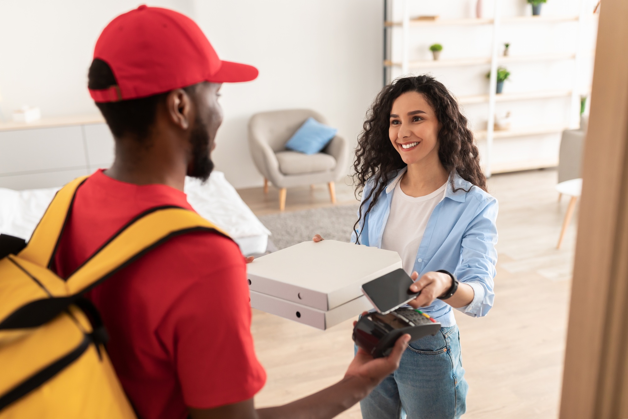 Black delivery man holding POS machine for payment