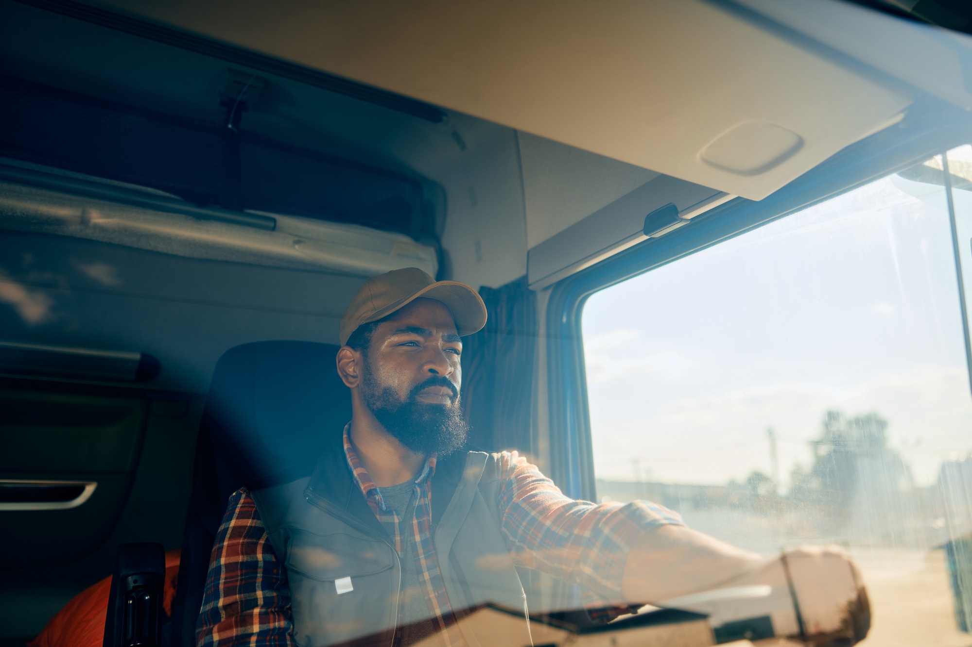 Black truck driver behind the steering wheel on the road.