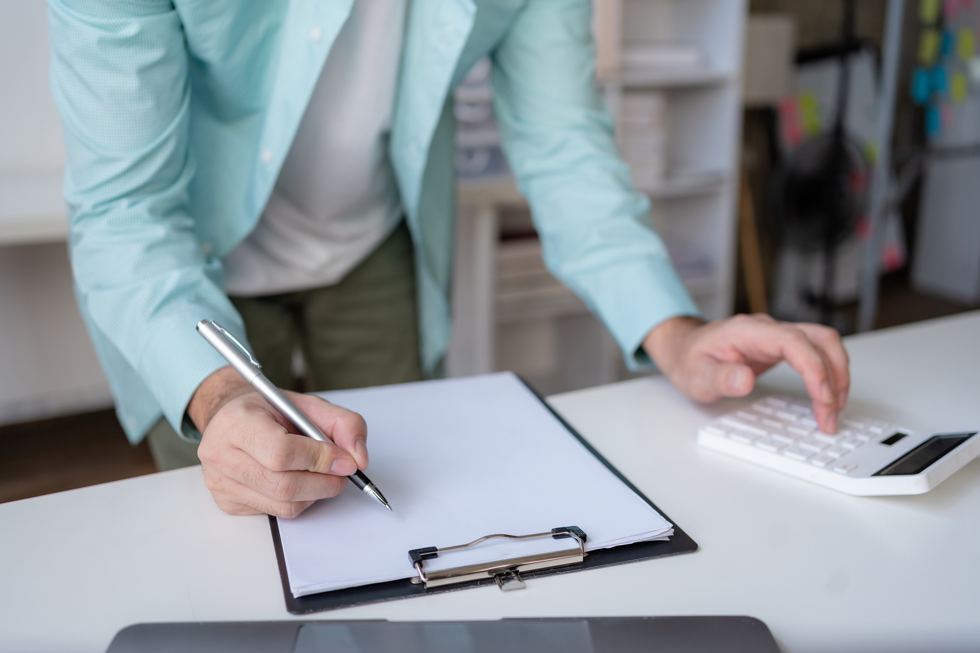 Business professional using a calculator and taking notes, financial planning or budgeting
