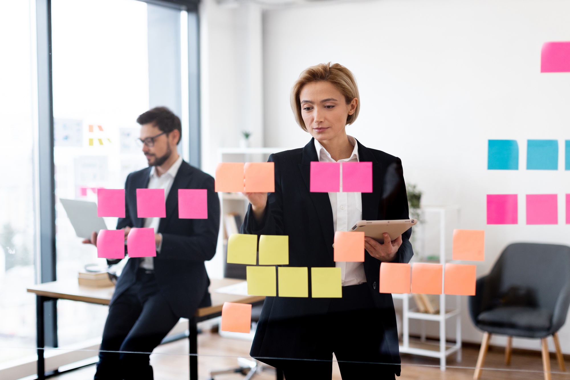 Business professionals brainstorming ideas using sticky notes on board