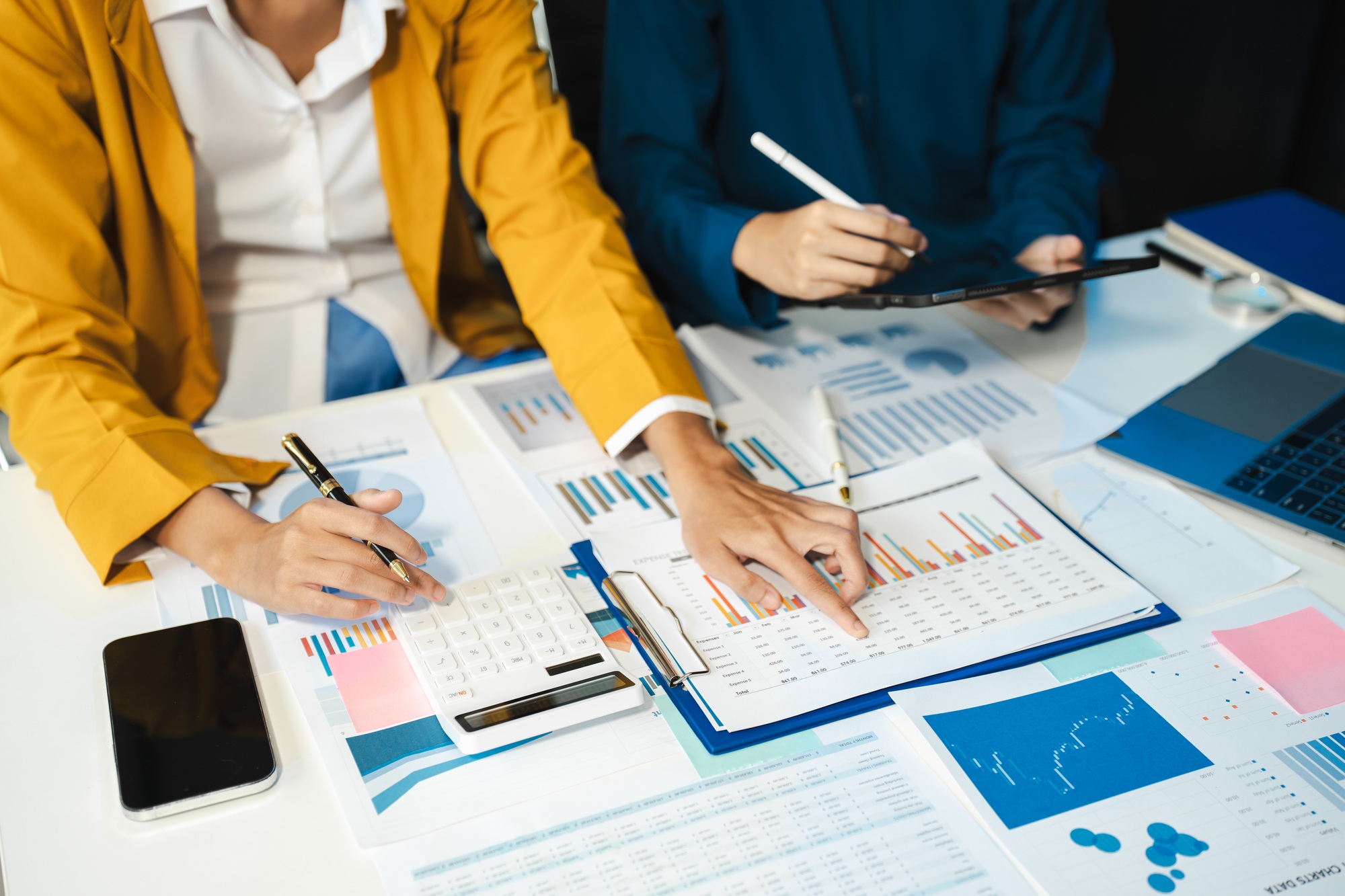 Business team working on desk office with using a calculator to calculate the numbers