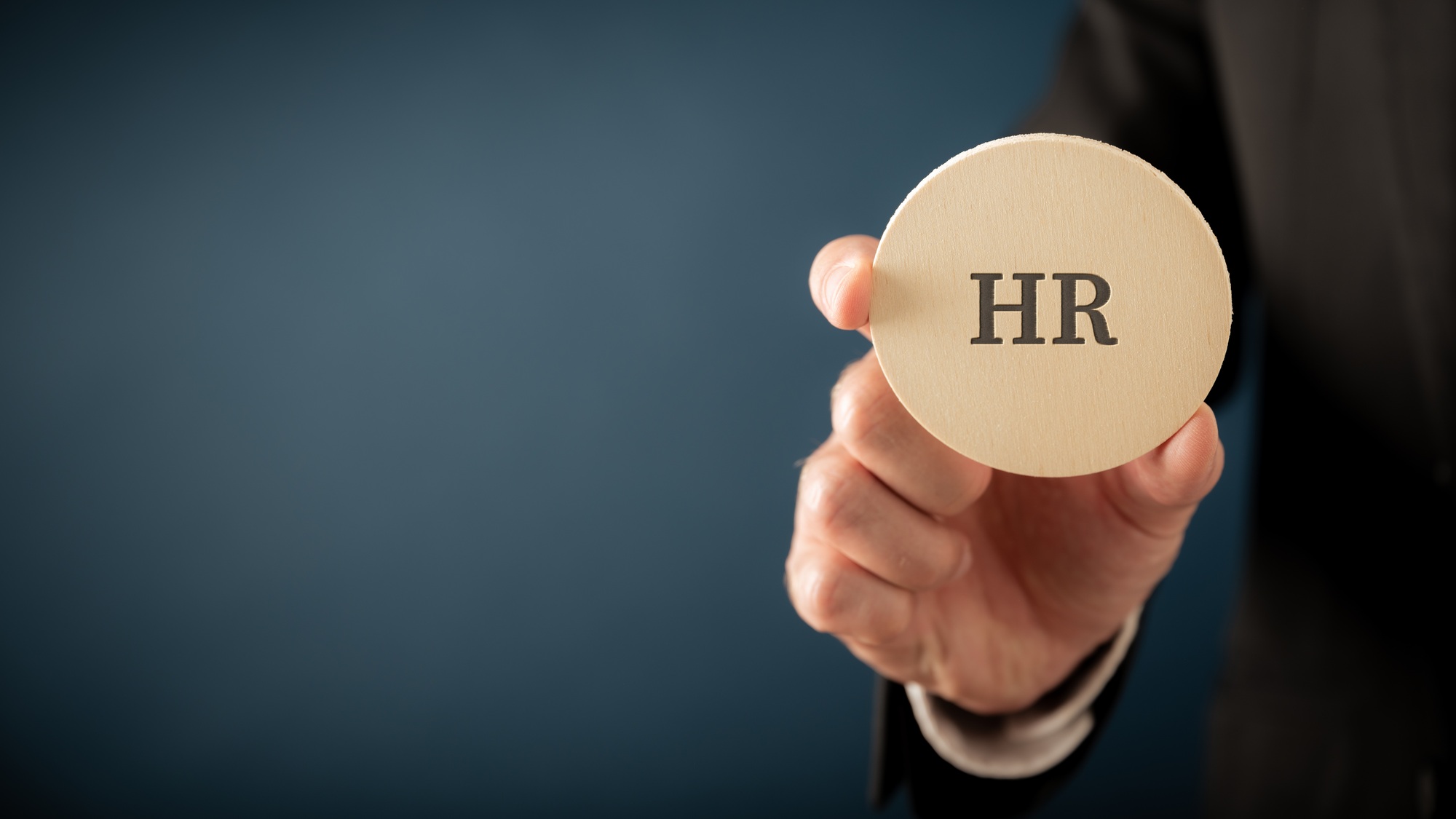 Businessman, an employer, holding a wooden cut circle wit an HR sign on it