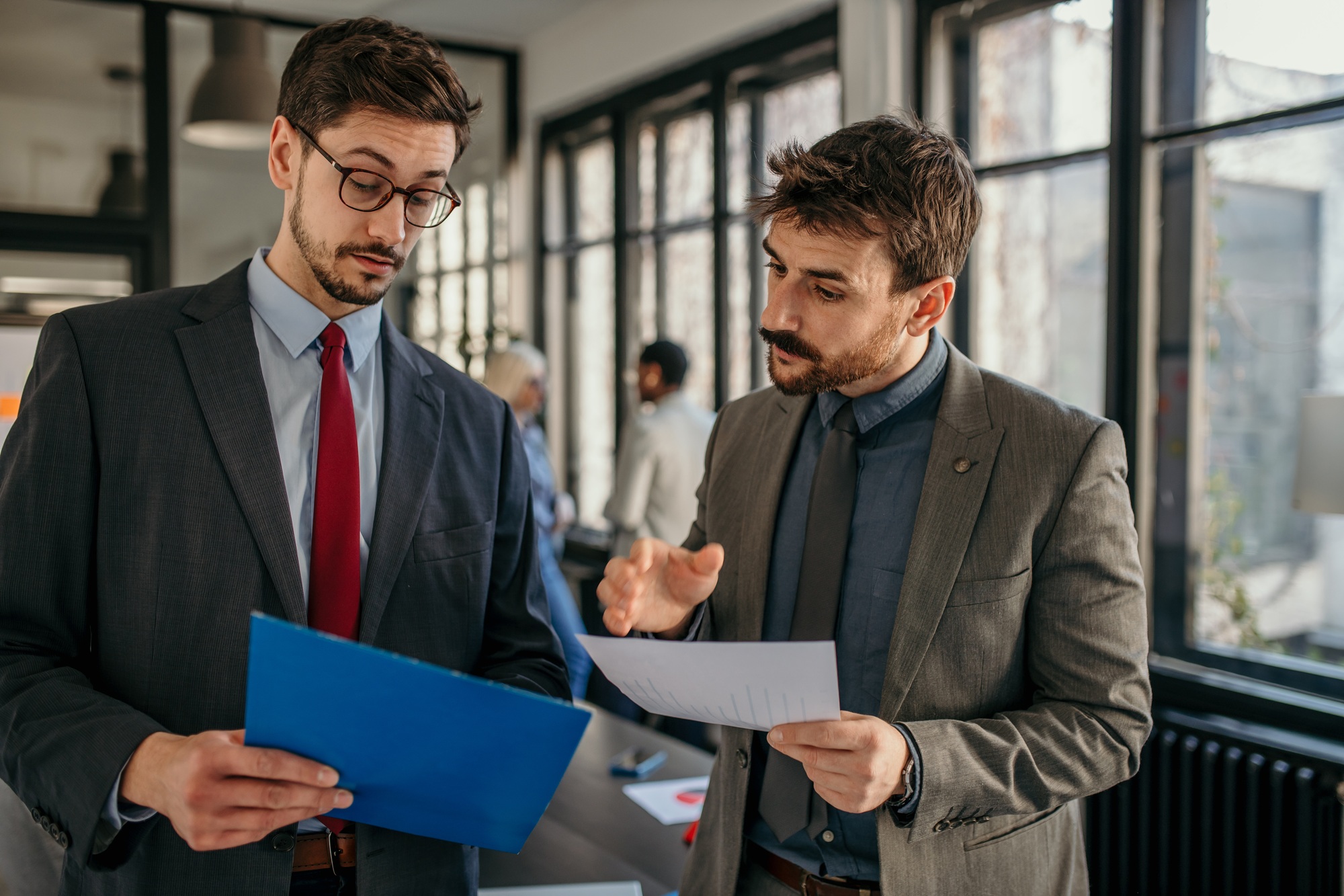 Businessmen discussing documents in modern office