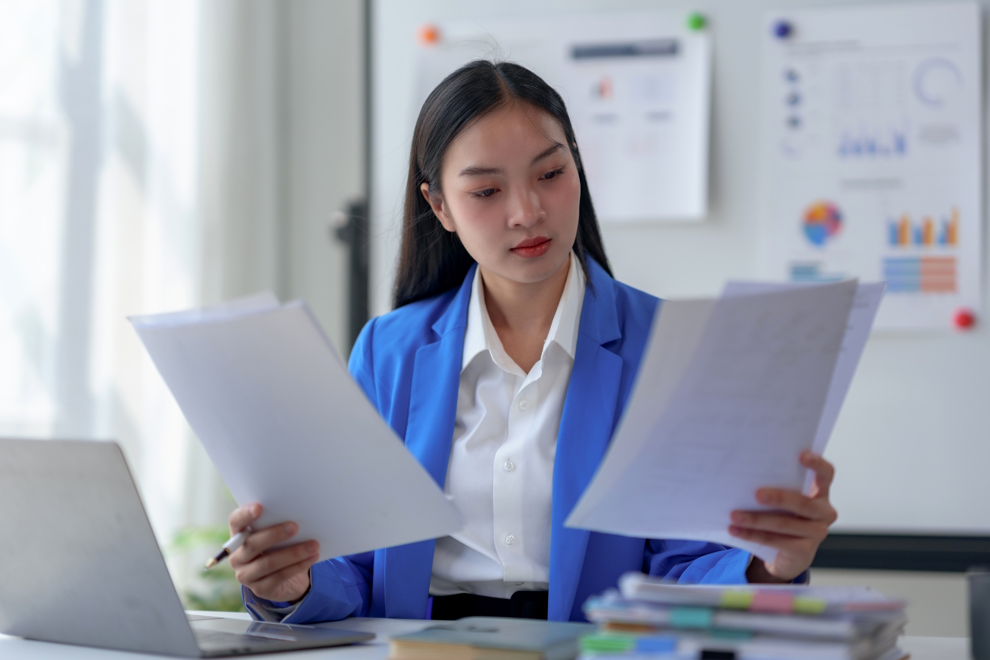 Businesswoman analyzing documents at her desk in a modern office