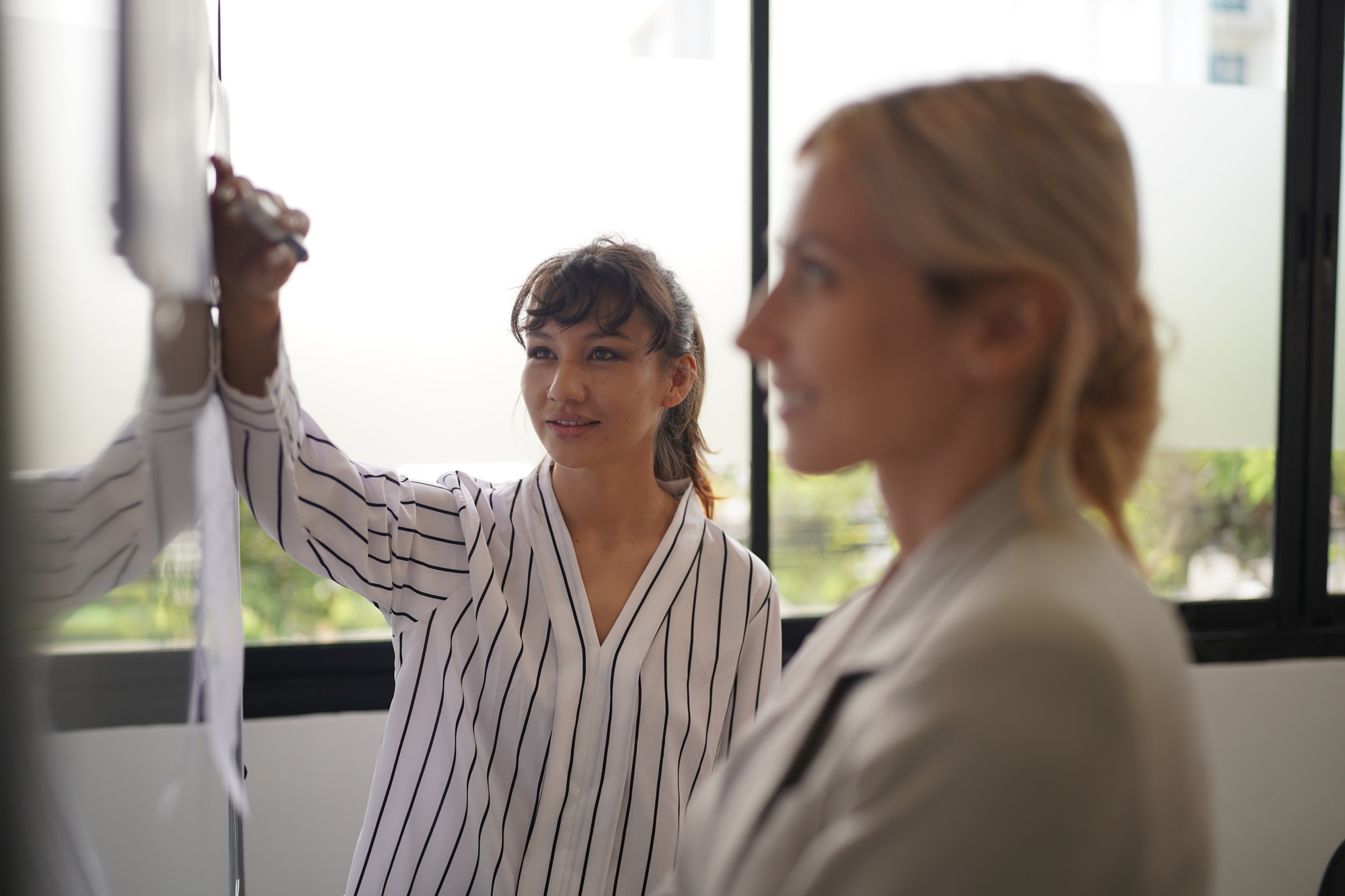 Businesswoman Pointing At Charts On whiteboard During Corporate Meeting in office.