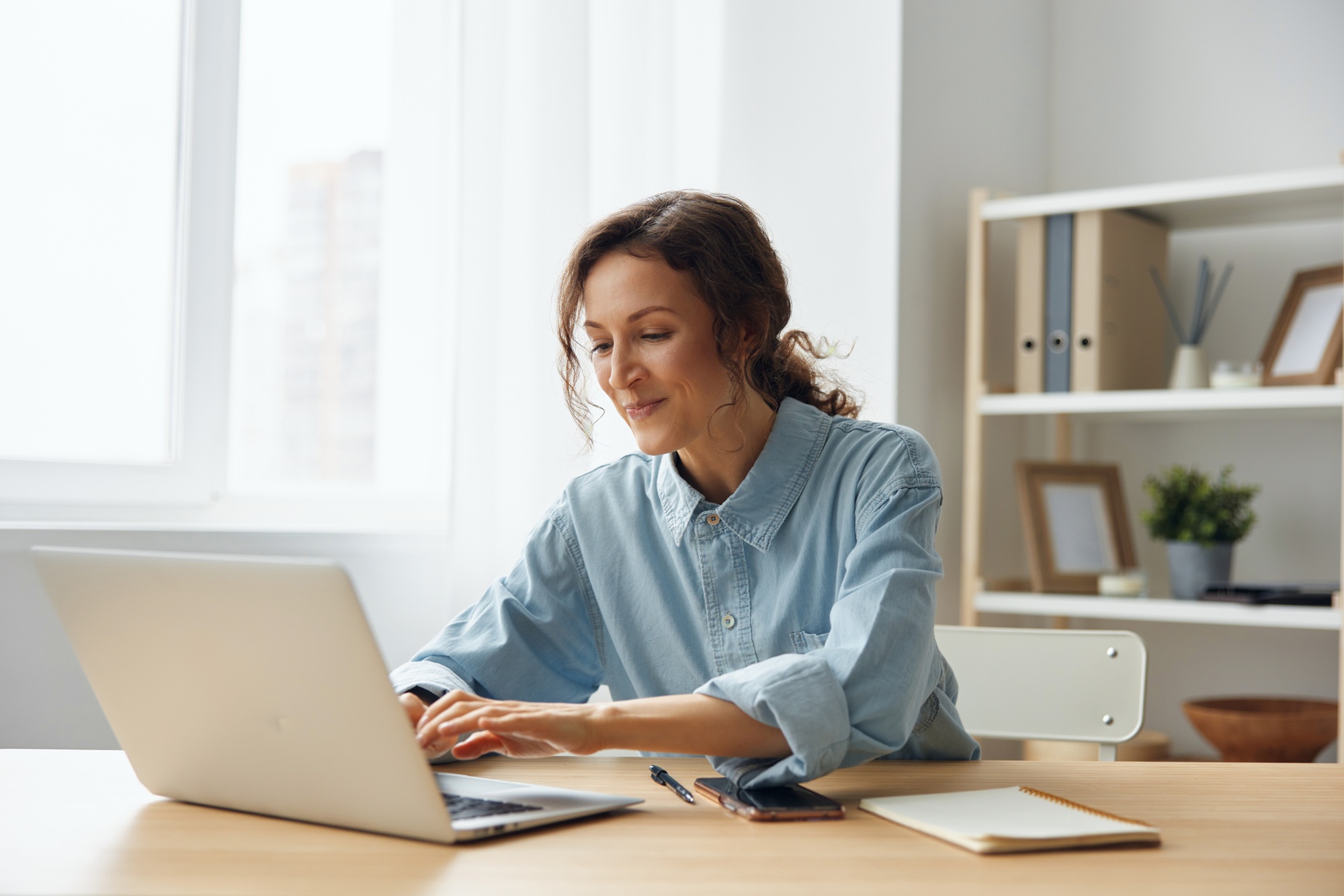 Cheerful adorable curly businesswoman worker freelancer chatting with client registers an order in