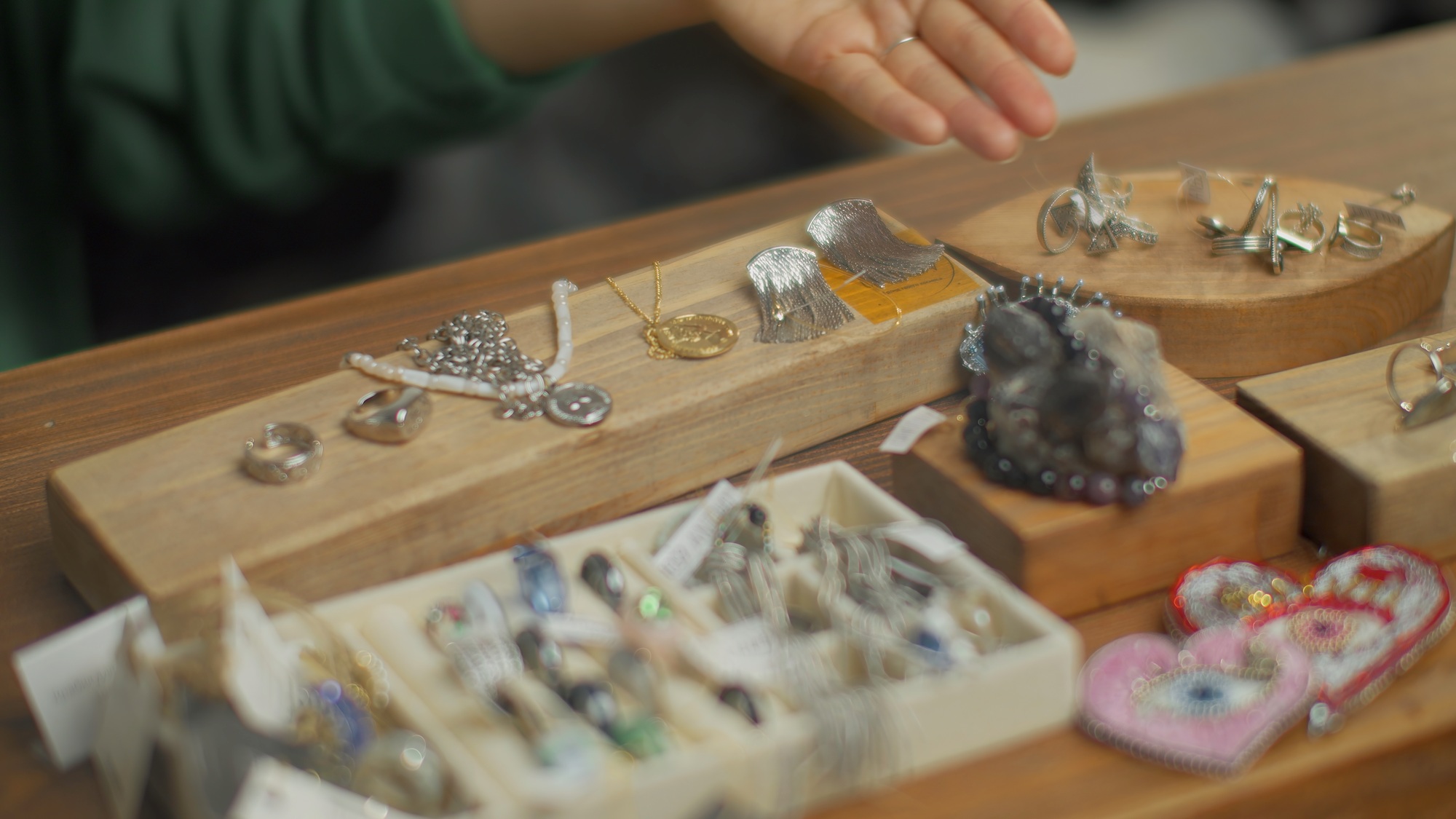 Close-up of woman showing stylish jewelry. Media. Beautiful handmade jewelry on counter. Handmade