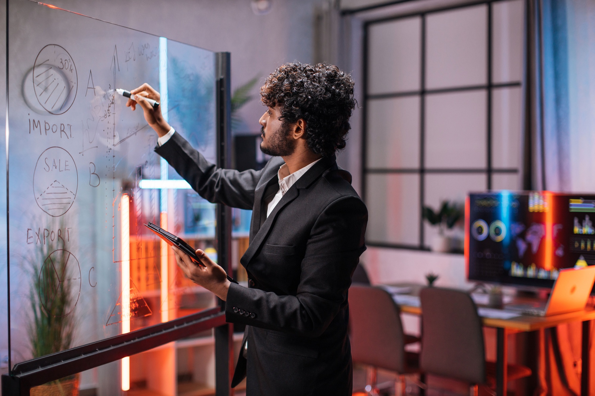 Confident businessman planning project on board in office