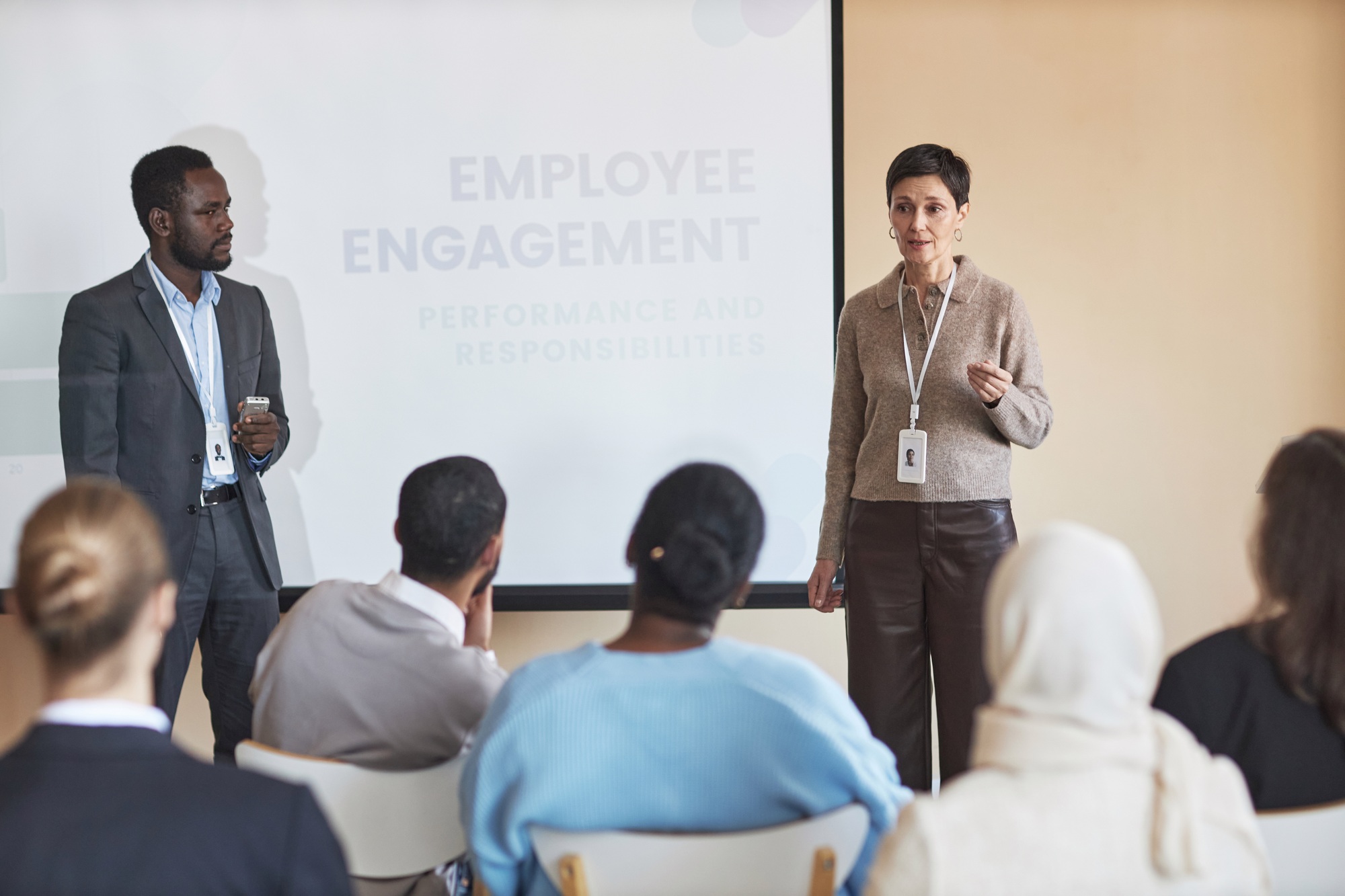 Confident mature female HR manager standing by whiteboard in front of audience