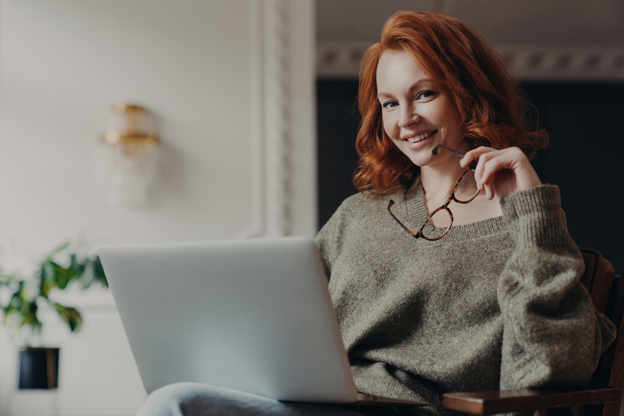 Confident redhead freelancer with spectacles works remotely, plans effective online project