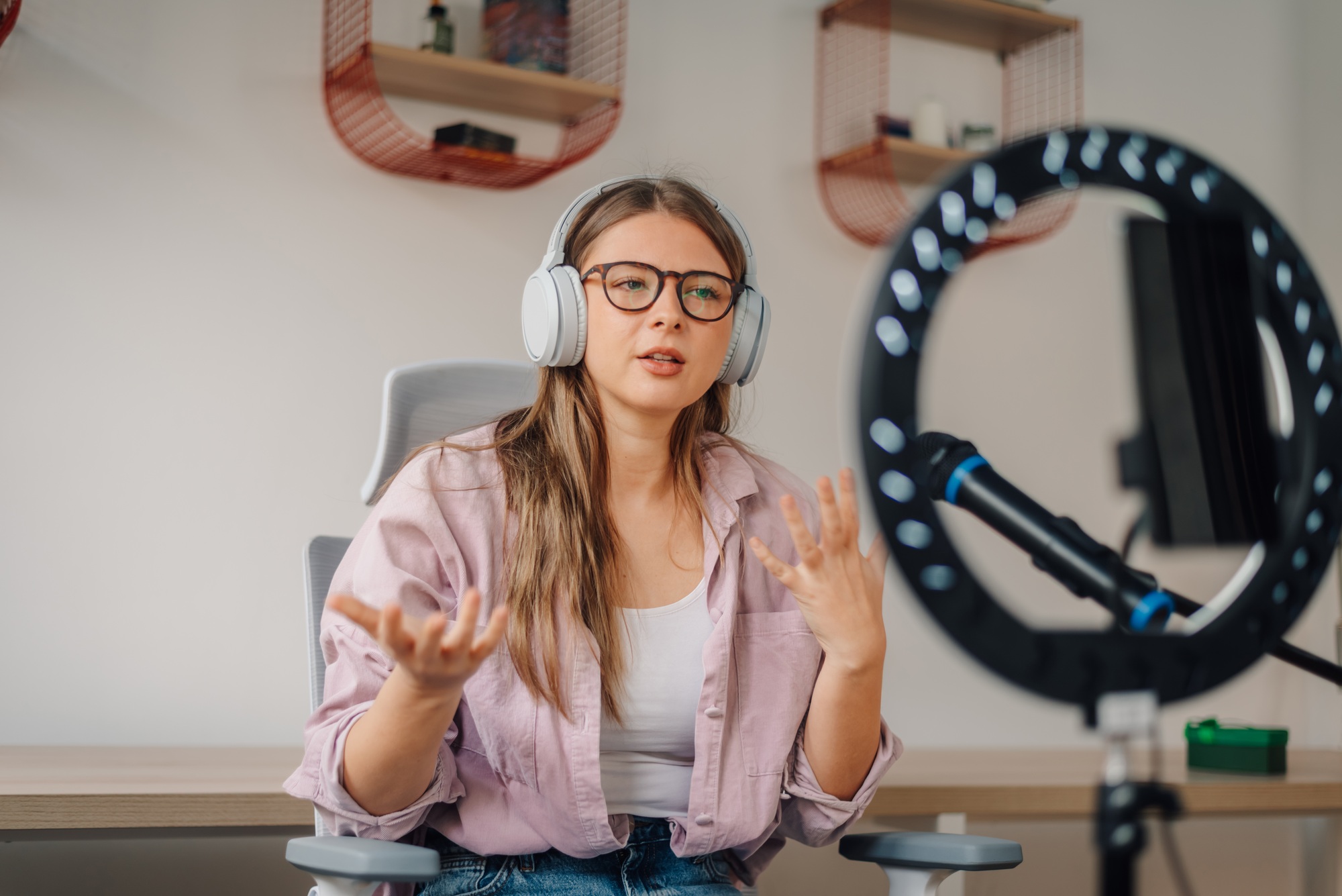 Content creator recording podcast wearing headphones and talking into microphone