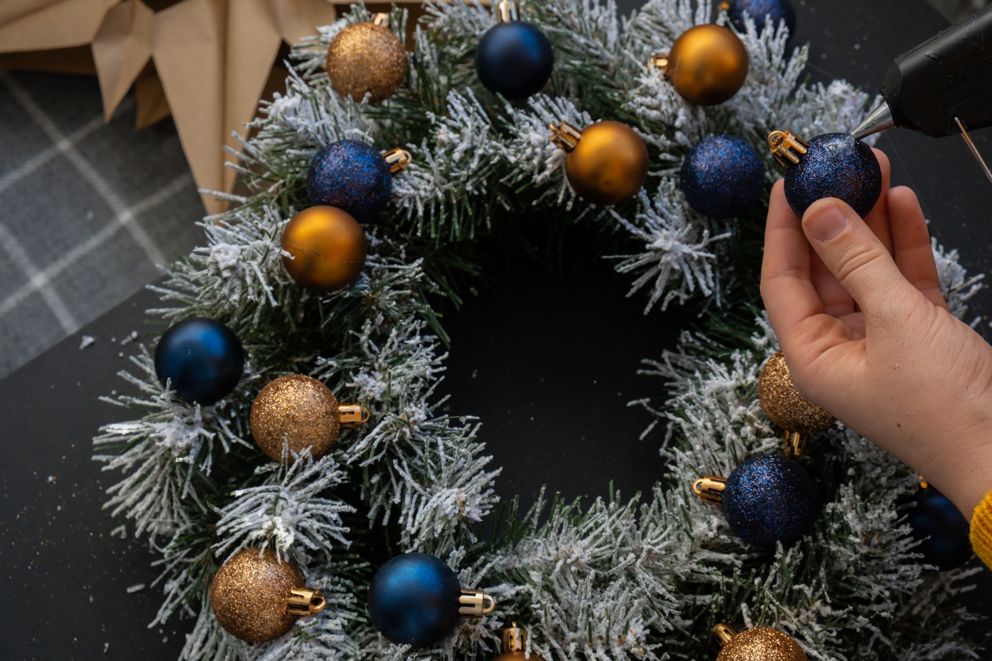 Crafter using hot glue DIY process of woman making Christmas arrangement with decor of blue and