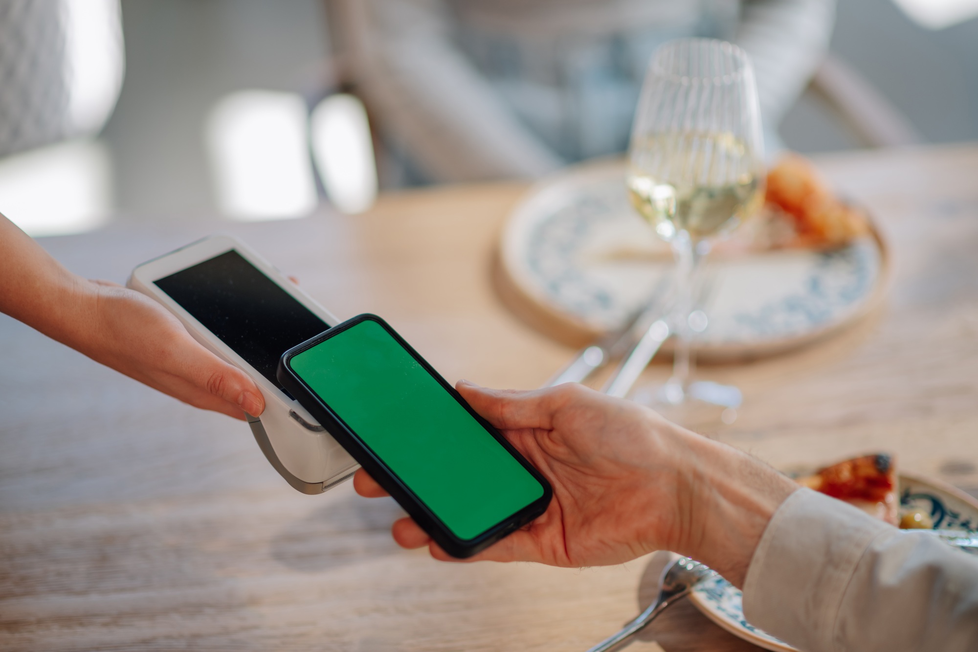 Customer paying restaurant bill with contactless nfc mobile payment on pos terminal