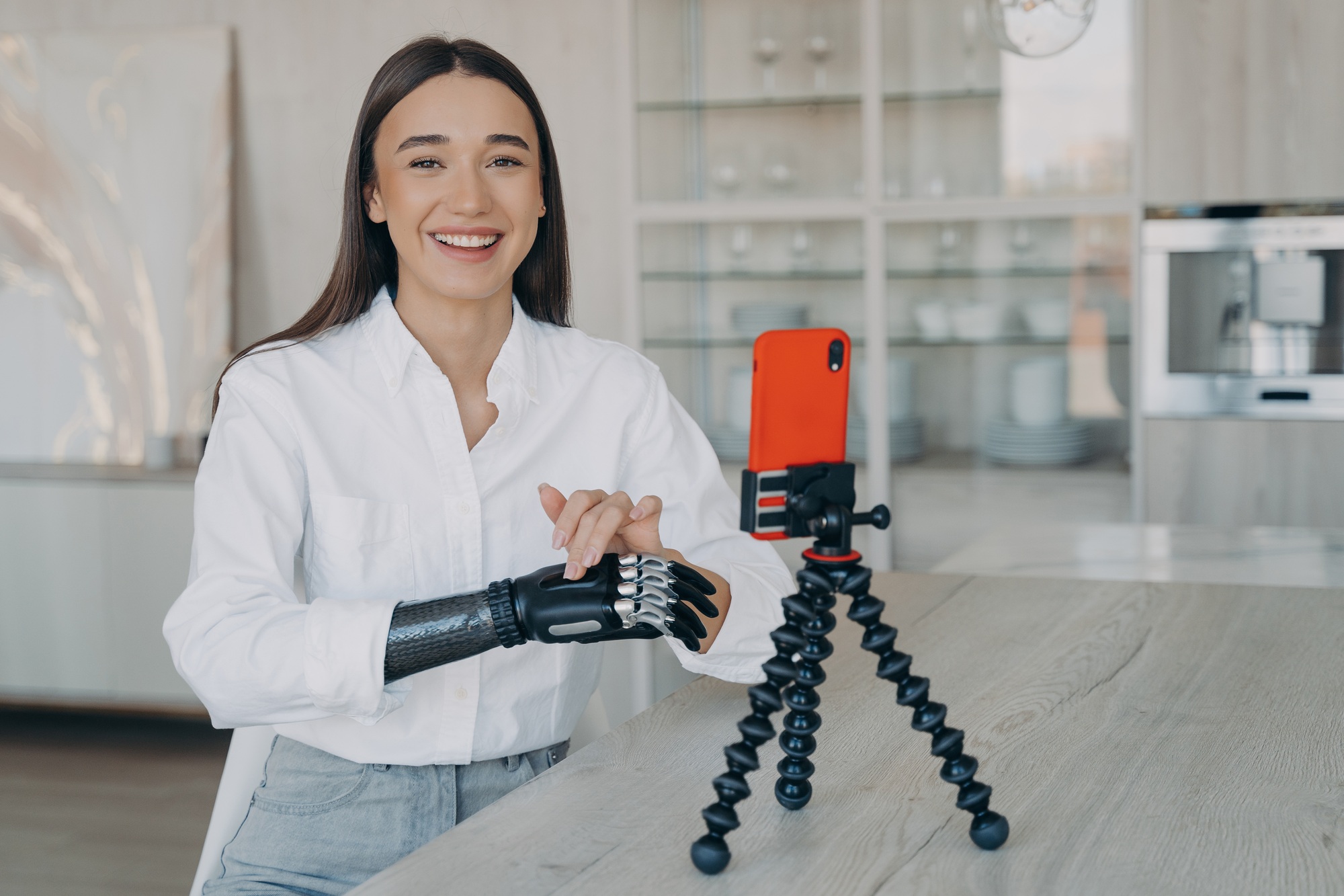 Disabled european woman streaming video in social media. Beauty blogger has myoelectric prosthesis.