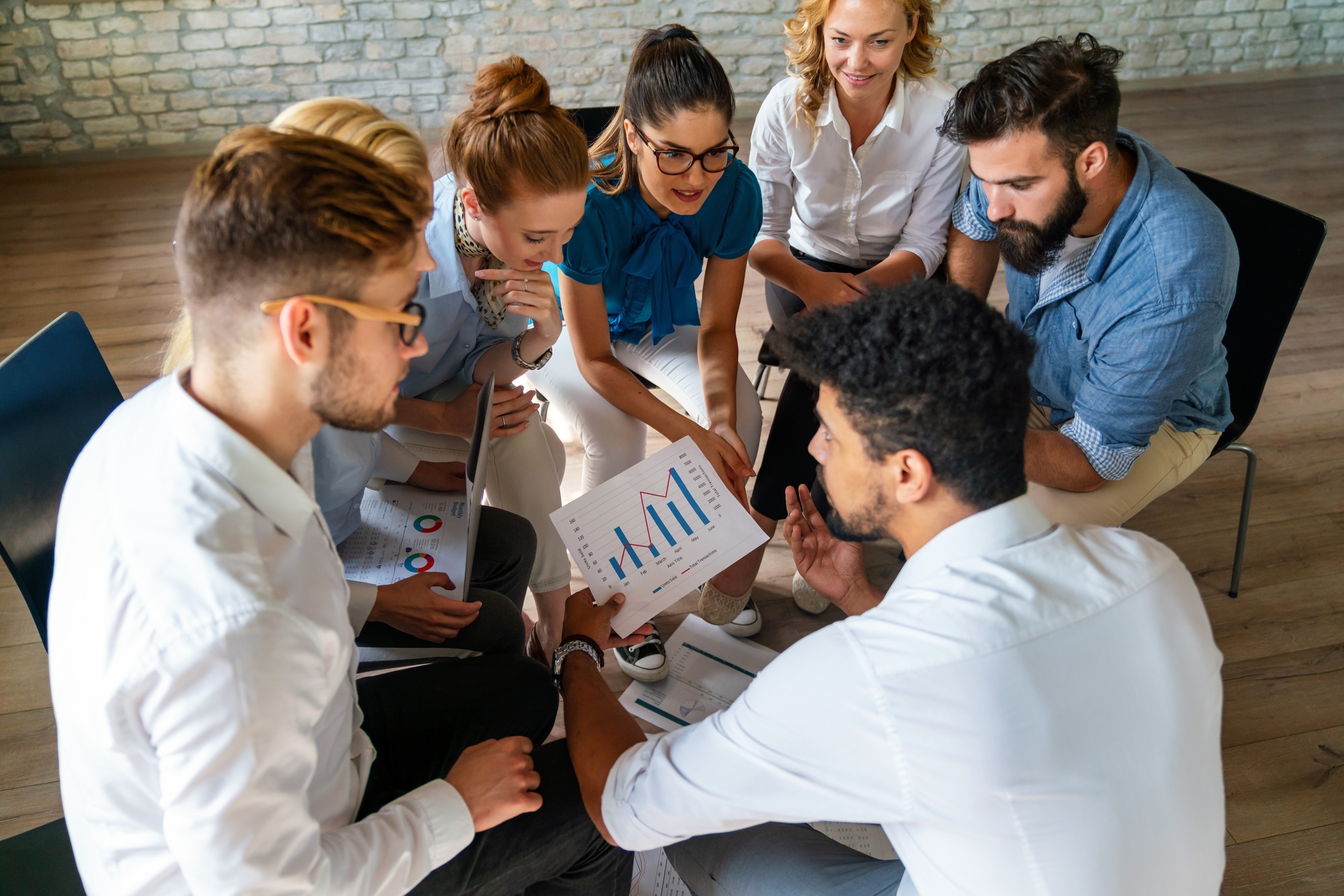 Diverse businesspeople discuss financial report in charts diagrams and graphs in meeting