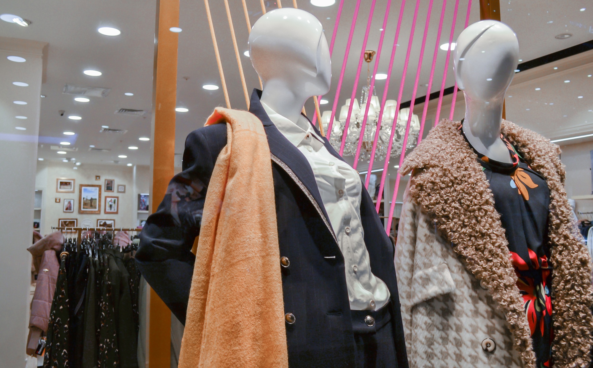 Female mannequins in autumn-winter clothes: boutique window on background of fashion store interior