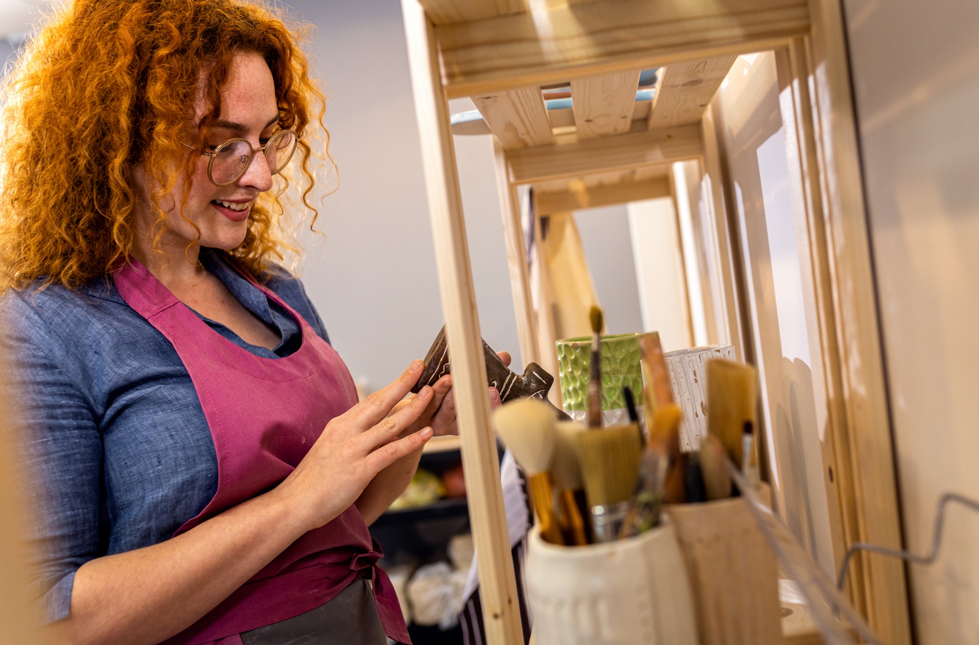 Female owner of pottery studio checking inventory on tablet device.