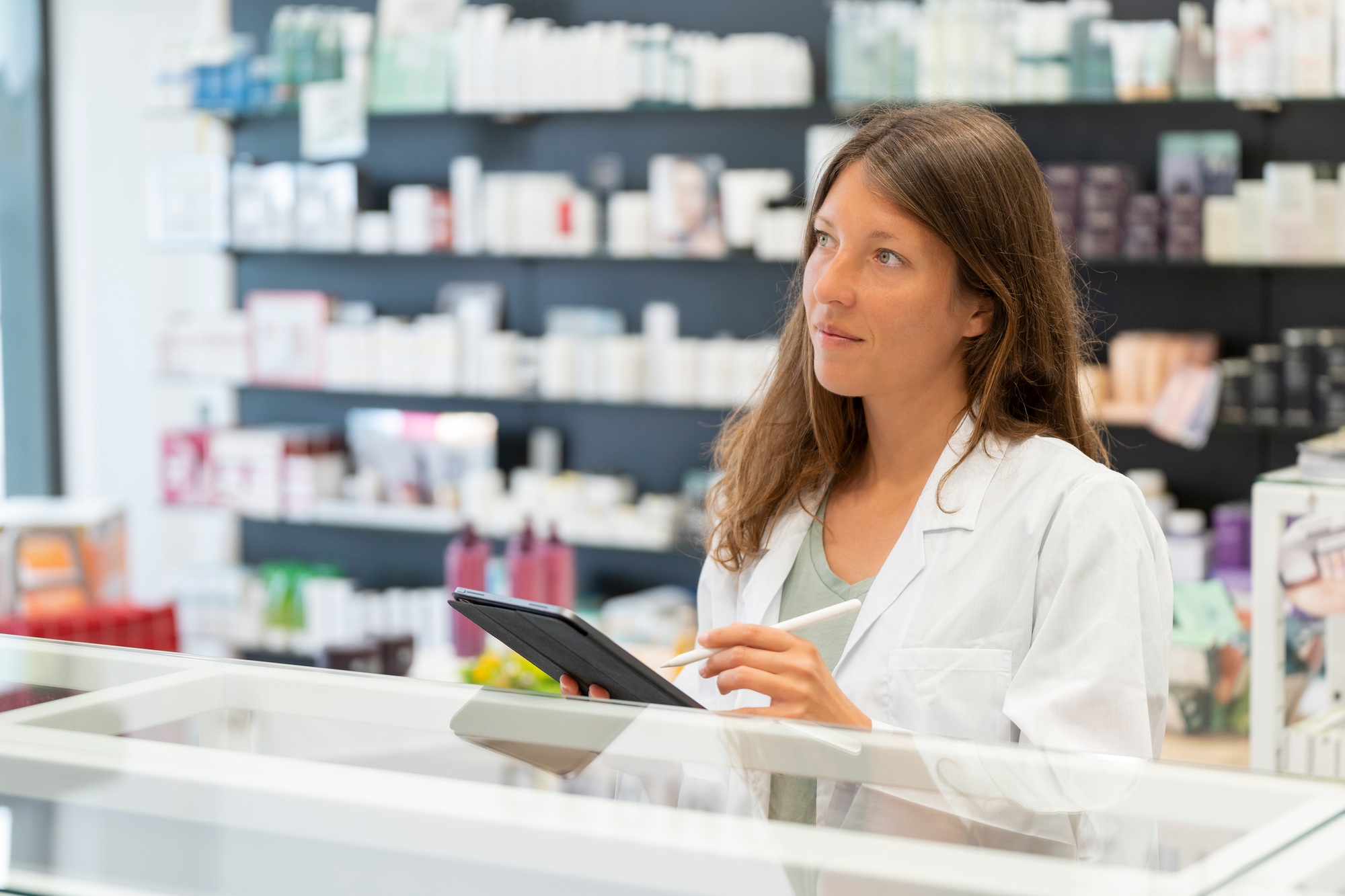 Female pharmacist using tablet for consultation in a well-stocked pharmacy