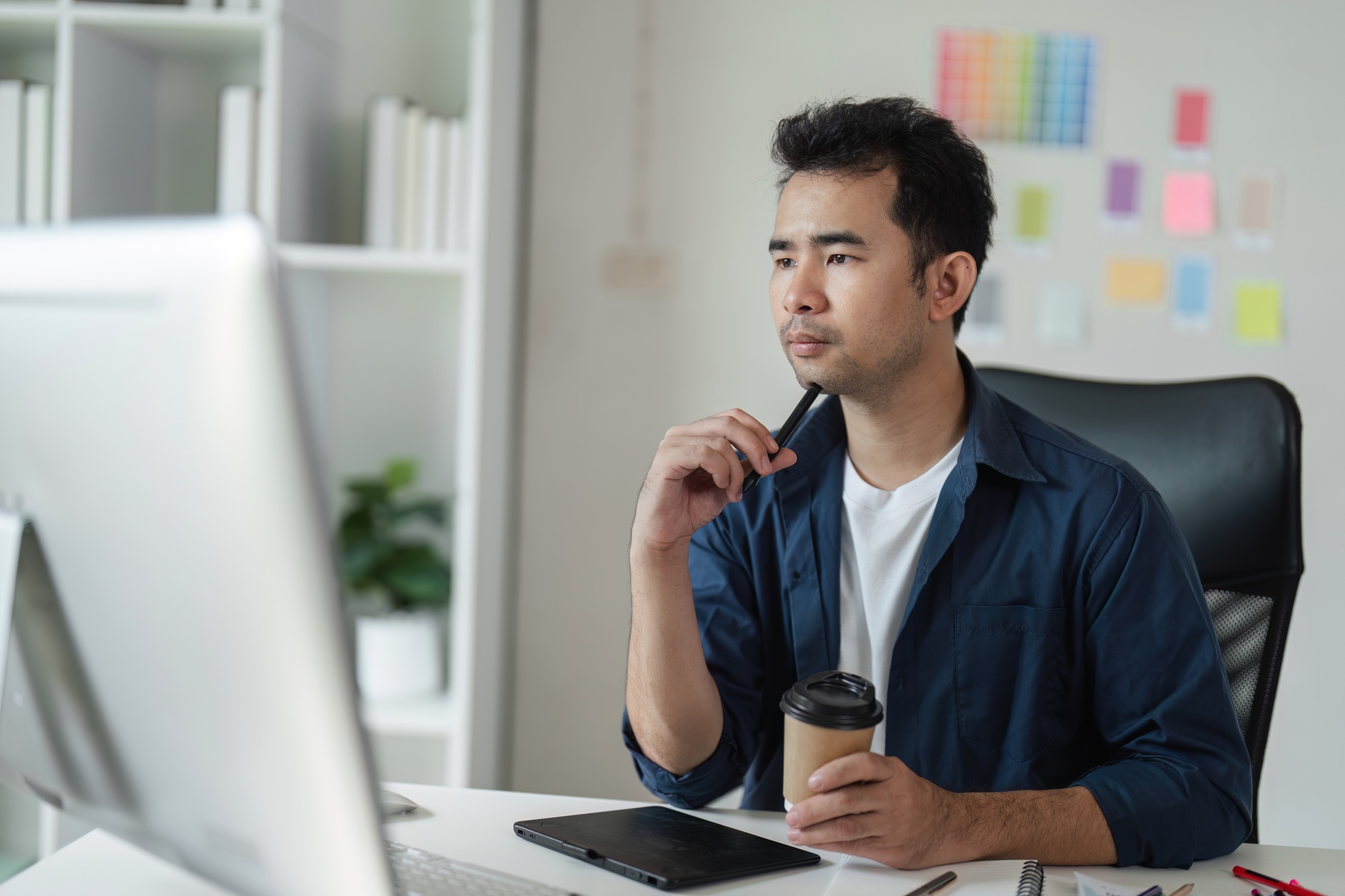 Focused Graphic Designer Strategizing a Creative Project in a Modern Office Environment with Digital