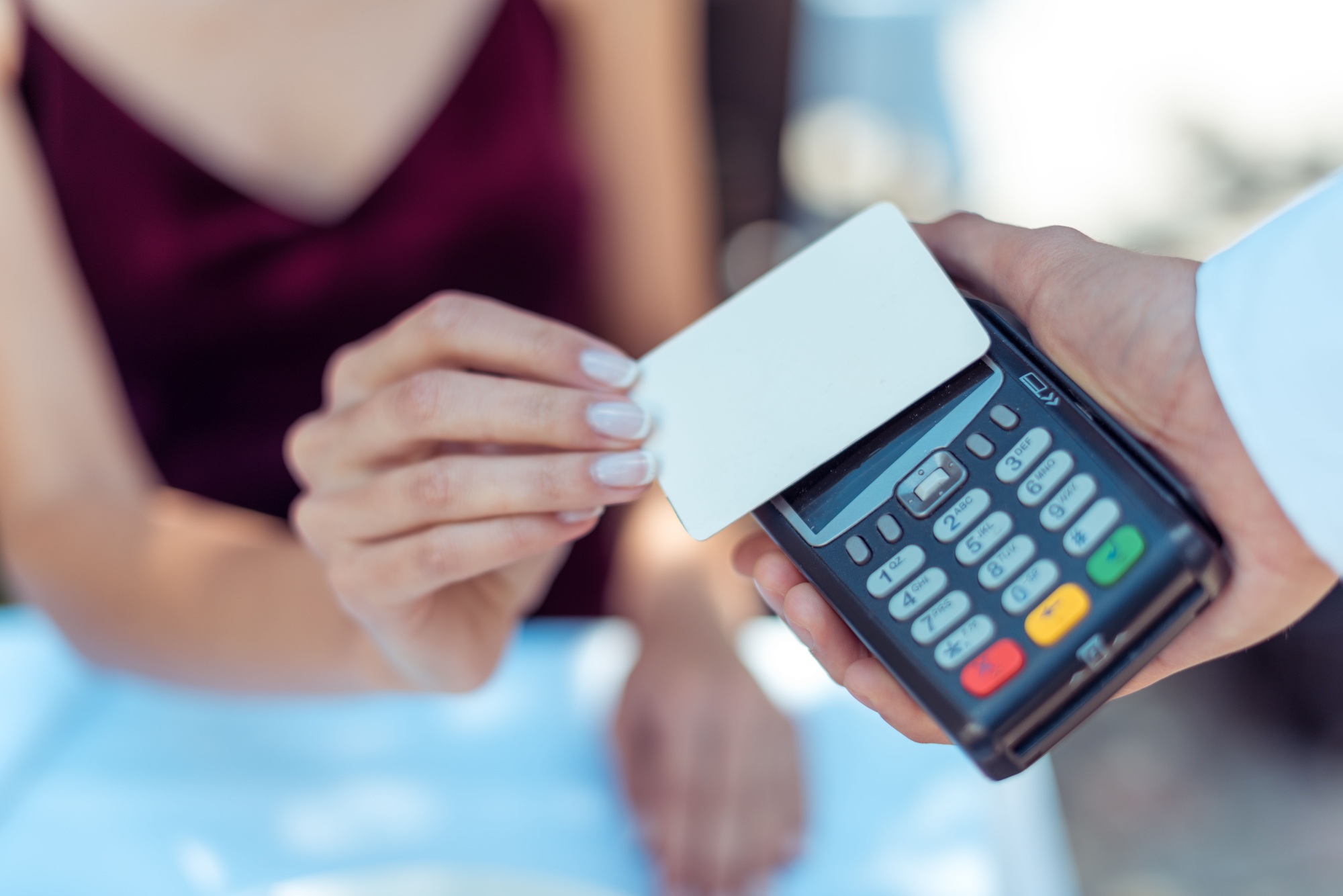 Close-up view woman using contactless credit card on pos terminal