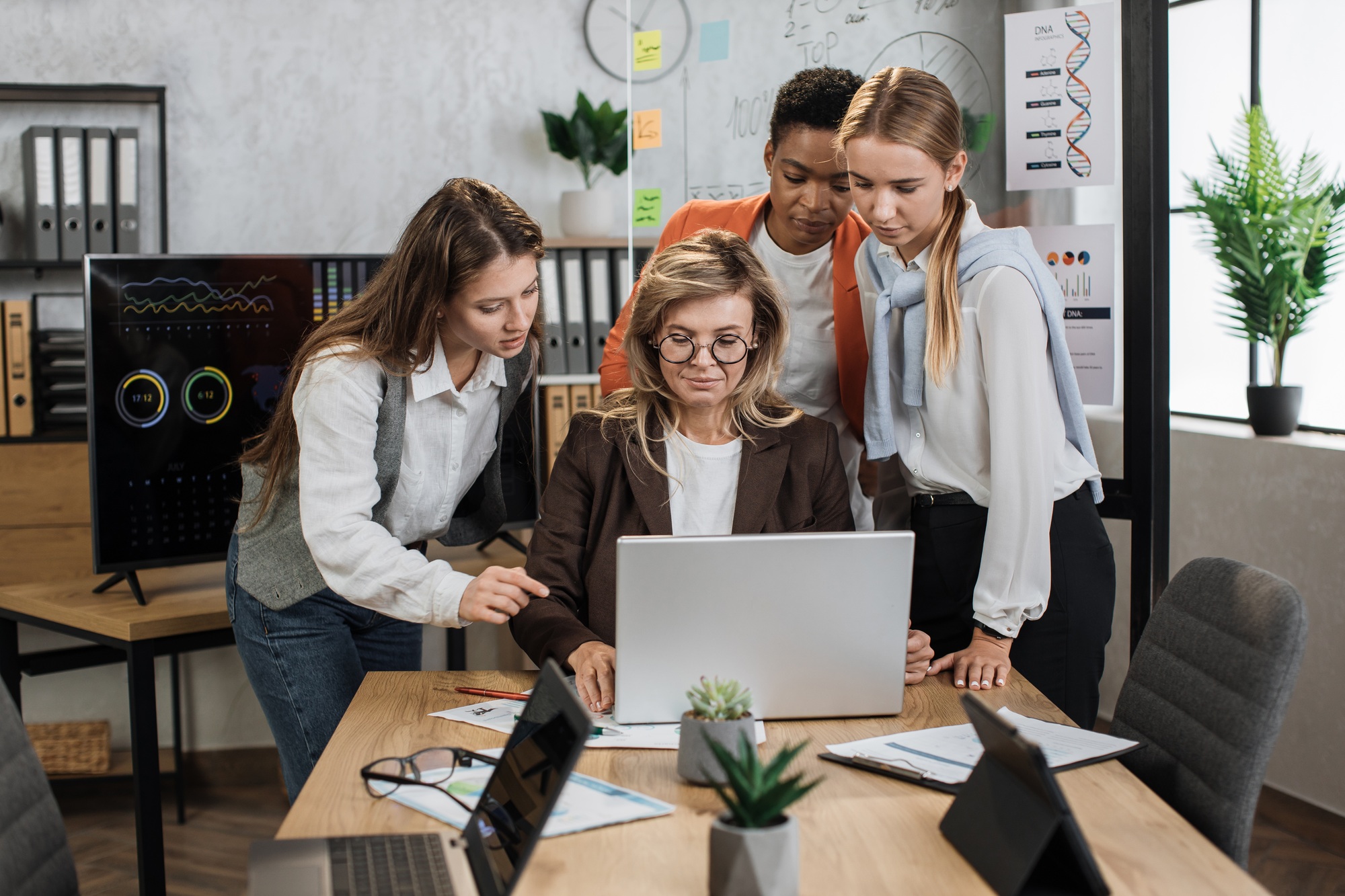 Group of confident high-skilled multiracial business women, standing at the table