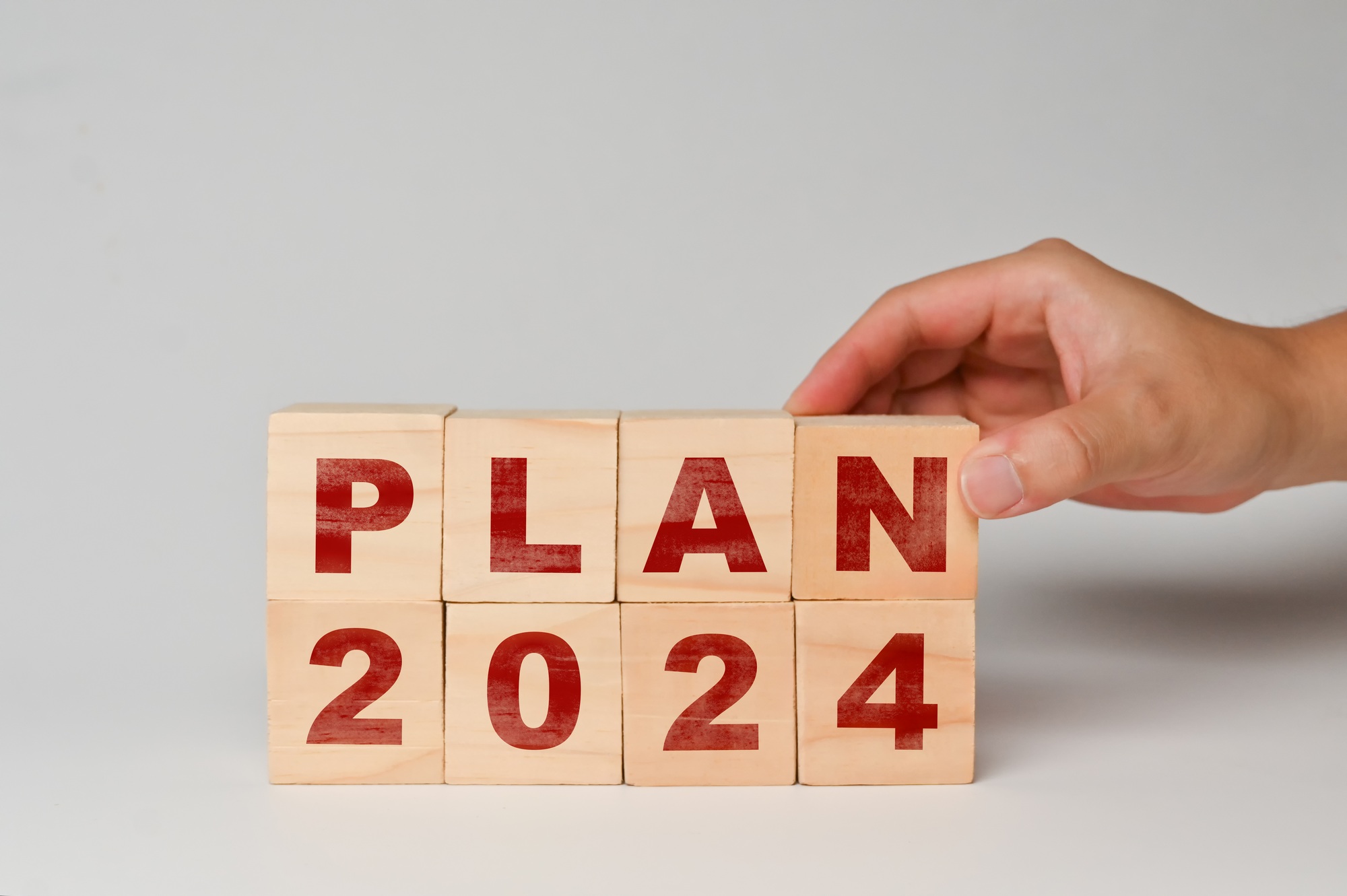Hand place wooden cubes with PLAN 2024 on white background. Business plan, goals and strategy.