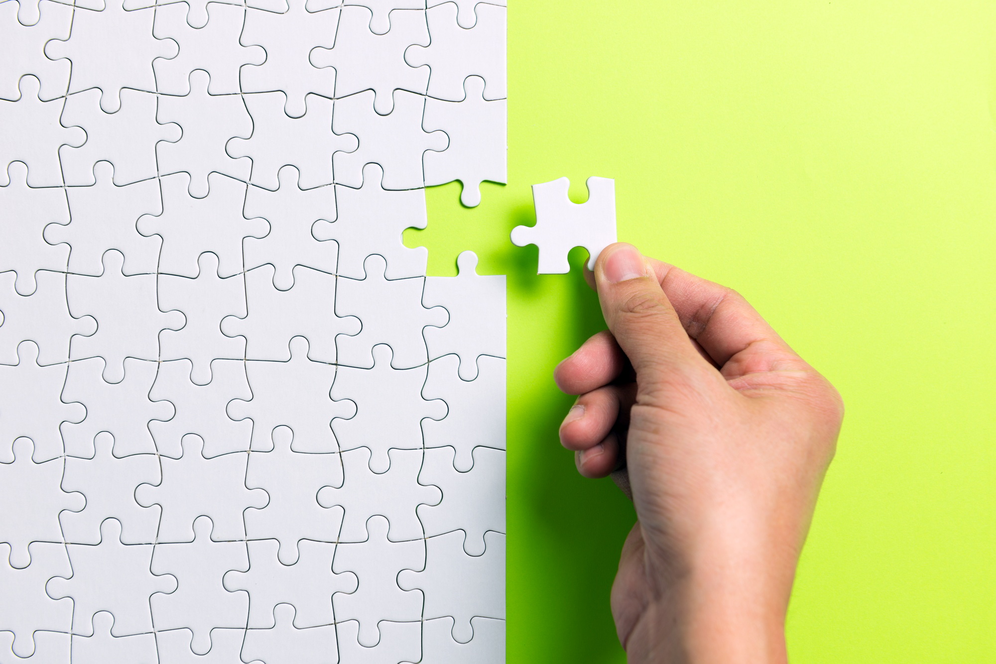 Hand putting the last piece of white puzzle for business concept or content background