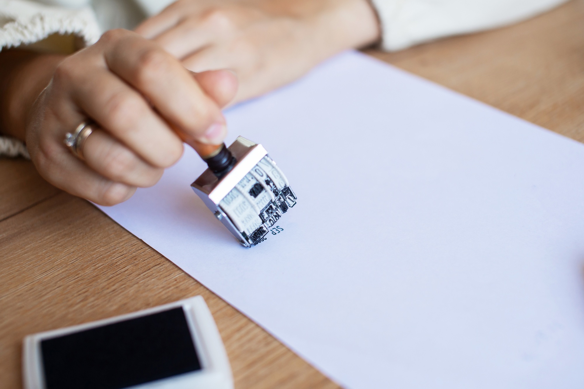 Hand Stamping Document on Desk: Legal, Approval, Office Setting