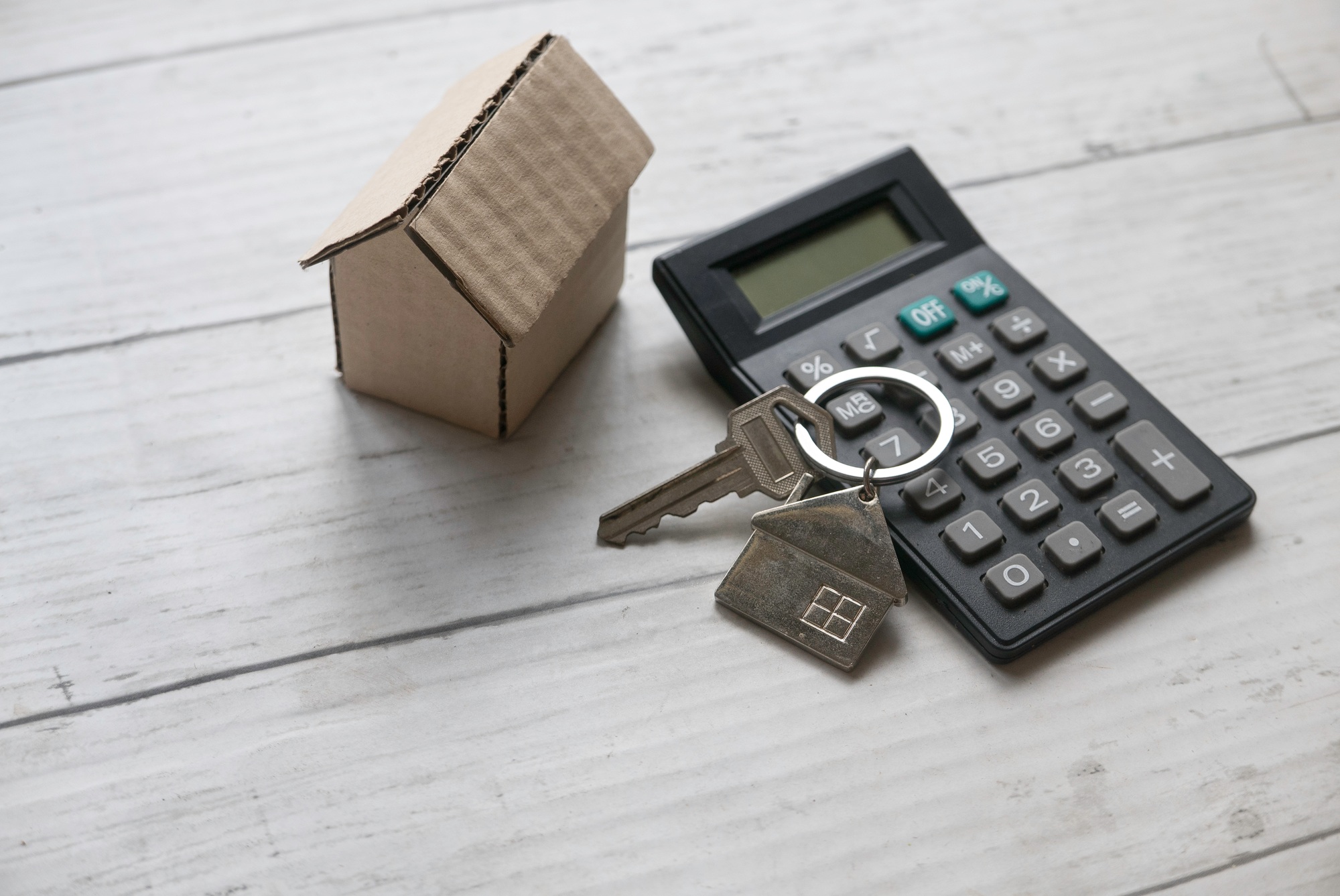 House key and calculator over a wooden background. Real estate concept.