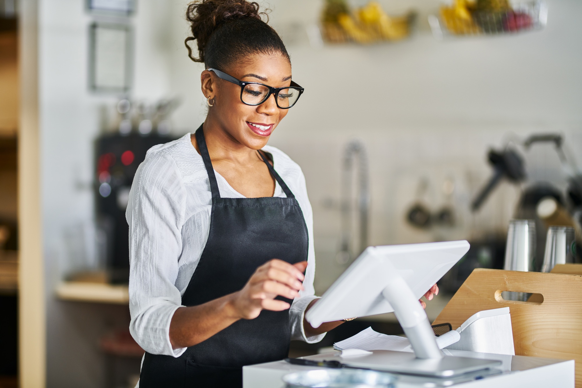 shop assistant placing order from notepad into pos point of sale terminal at register in restaurant