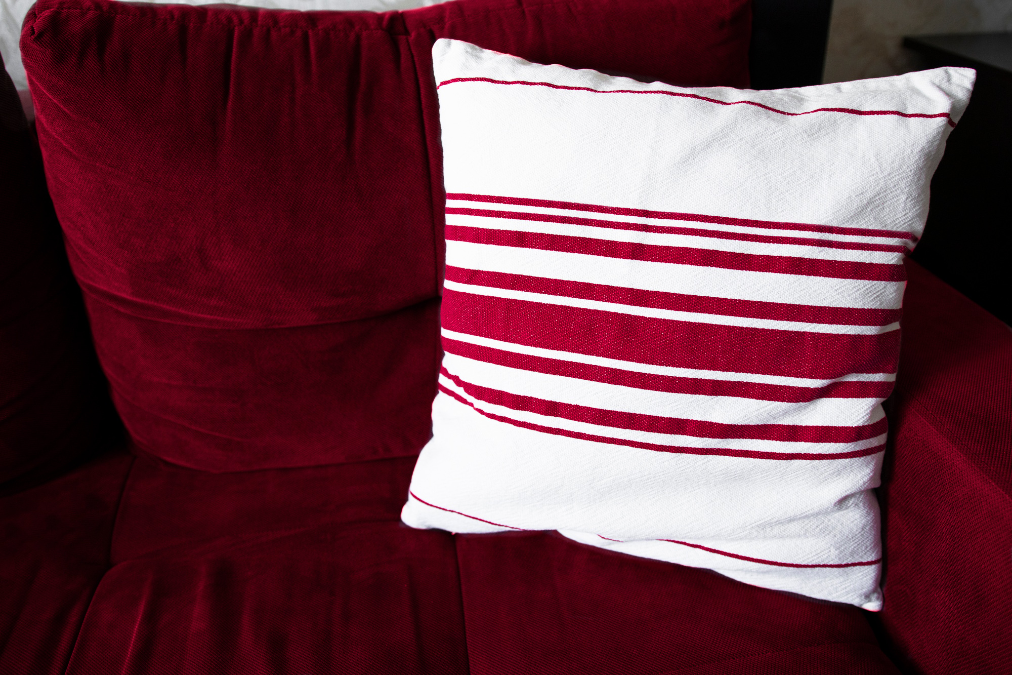 Living room interior with sofa and decorative pillow close-up. Viva magenta color of the year 2023