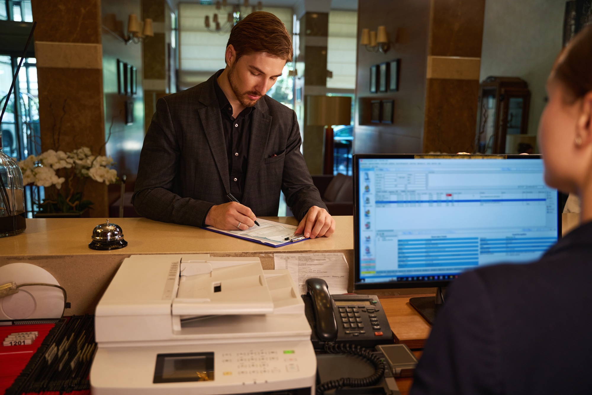 Male visitor filling registration form at reception desk