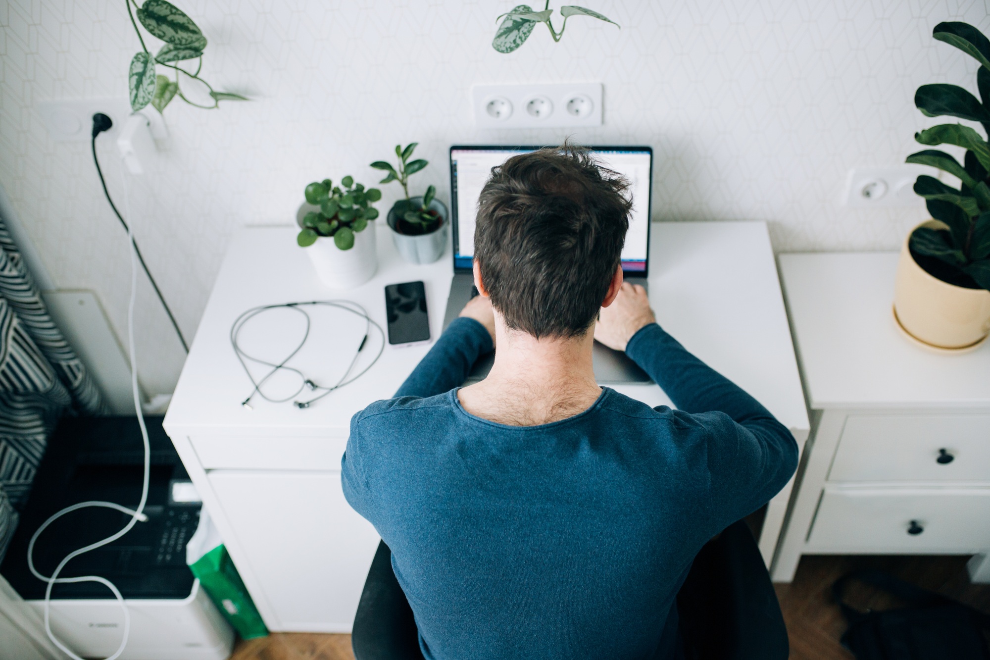 Man sitting at computer desk looking at computer code, programming, developer