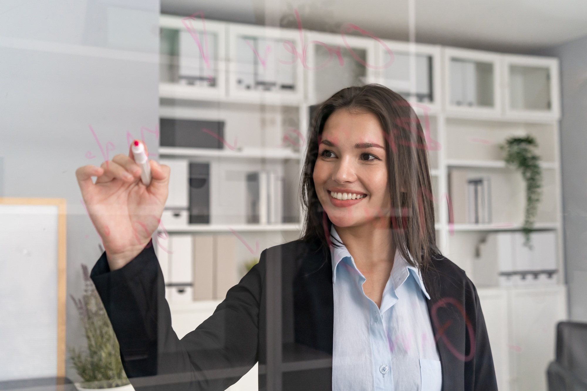 Mixed race businesswoman taking note on board in a conference room.