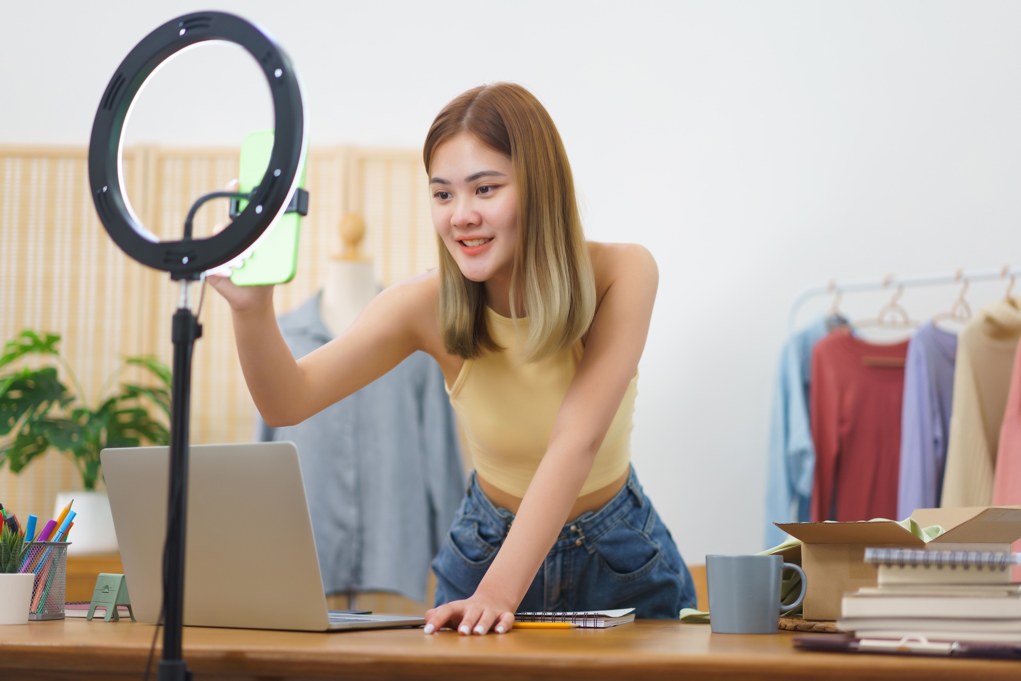 Online selling concept, Fashion designer checks smartphone to prepare live streaming sells clothes