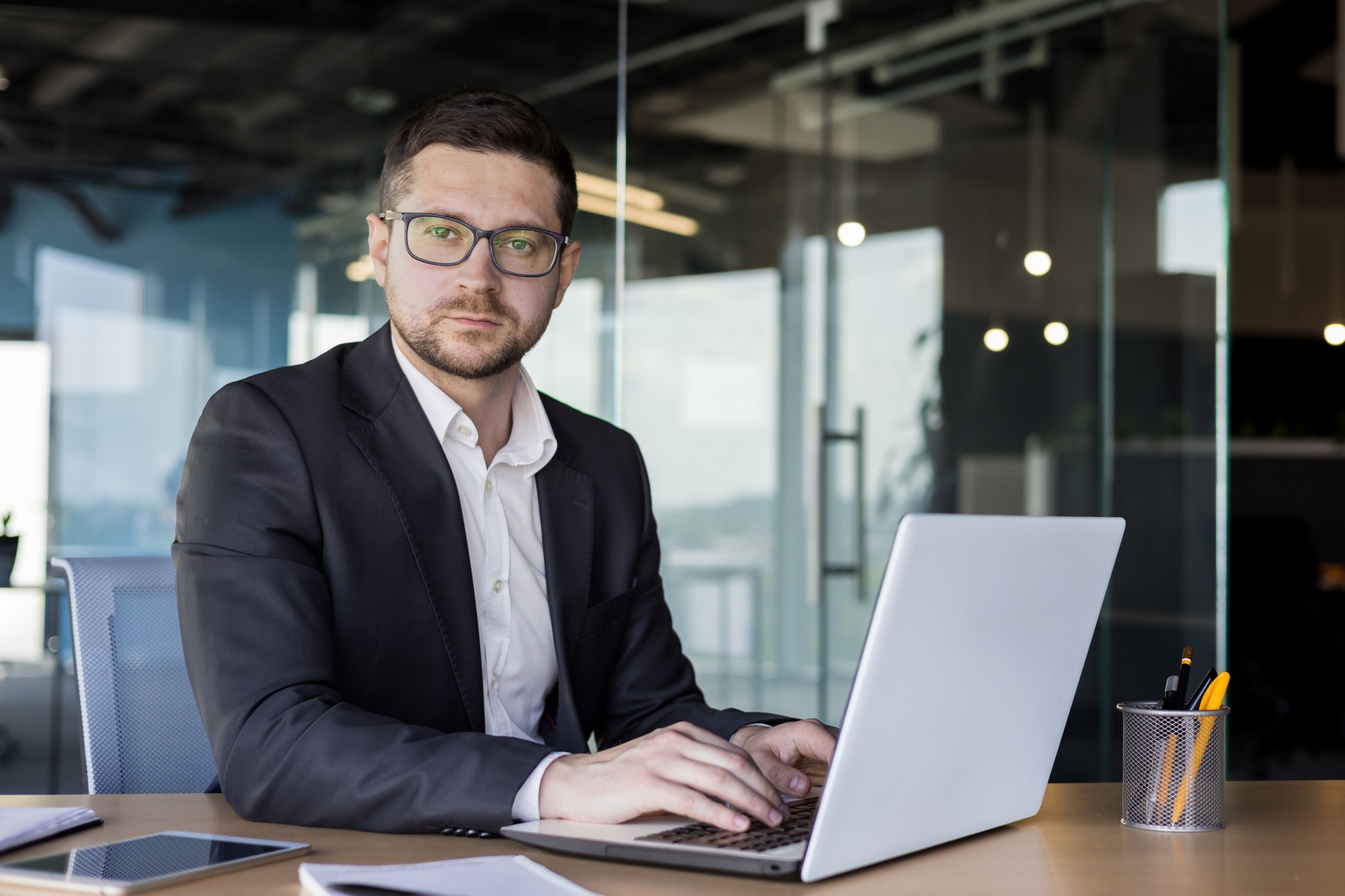 Portrait of a young man, a businessman, a lawyer, who works in an office at a desk and concentrates