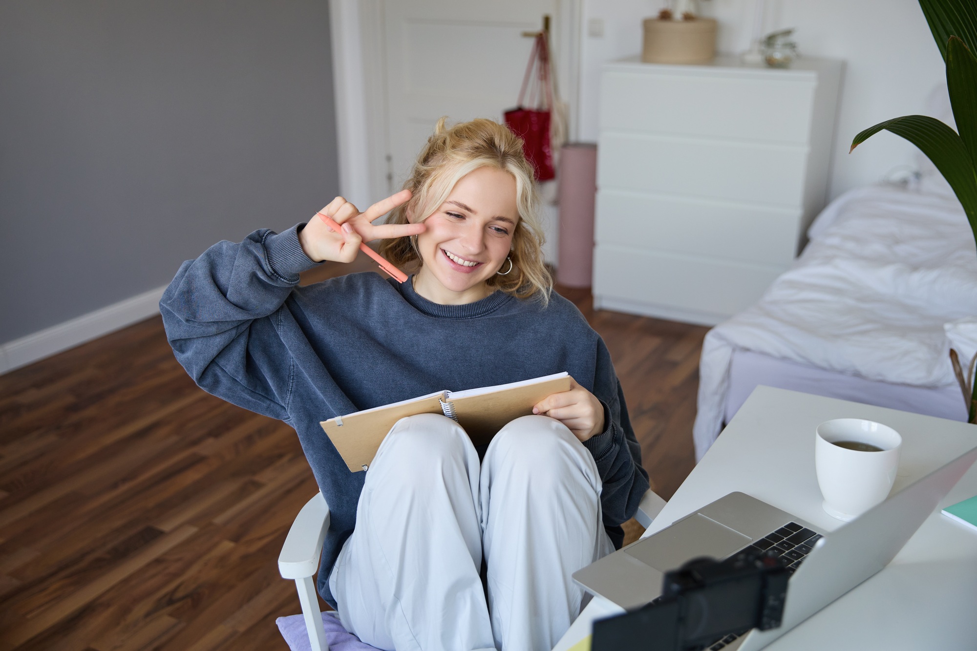 Portrait of smiling cute woman, lifestyle blogger, sits in her room with daily journal or planner
