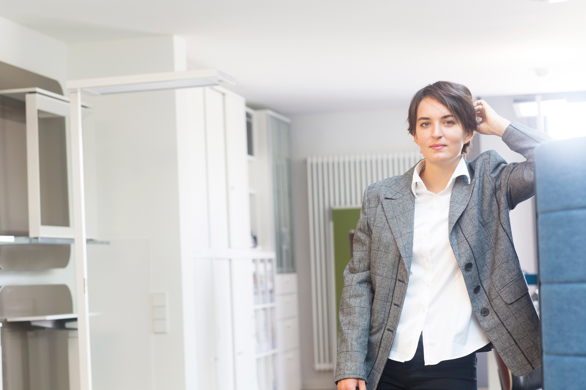 Portrait of young female sales manager leaning against office partition in office furniture store