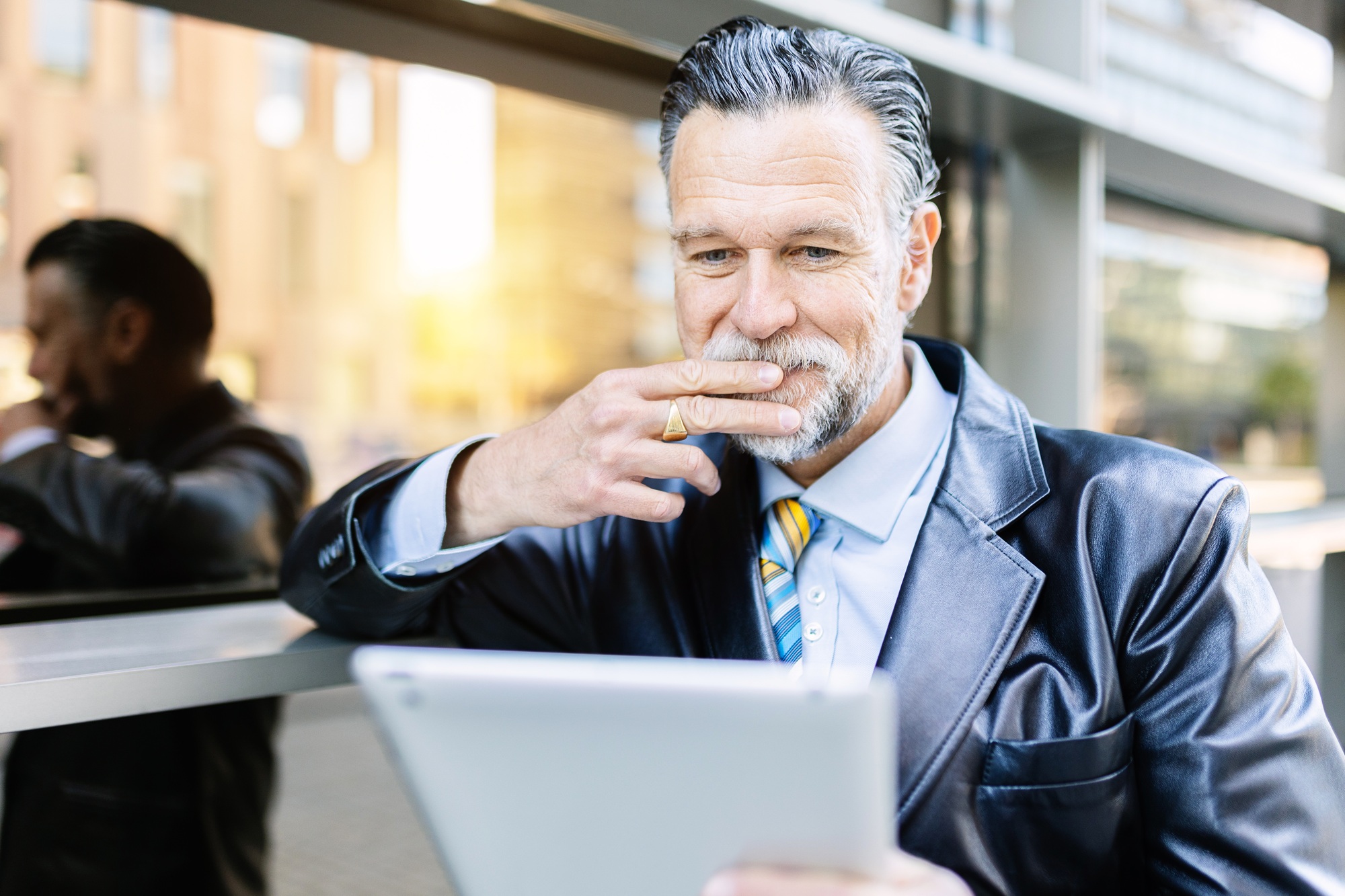 Senior executive sales businessman reading news on digital tablet