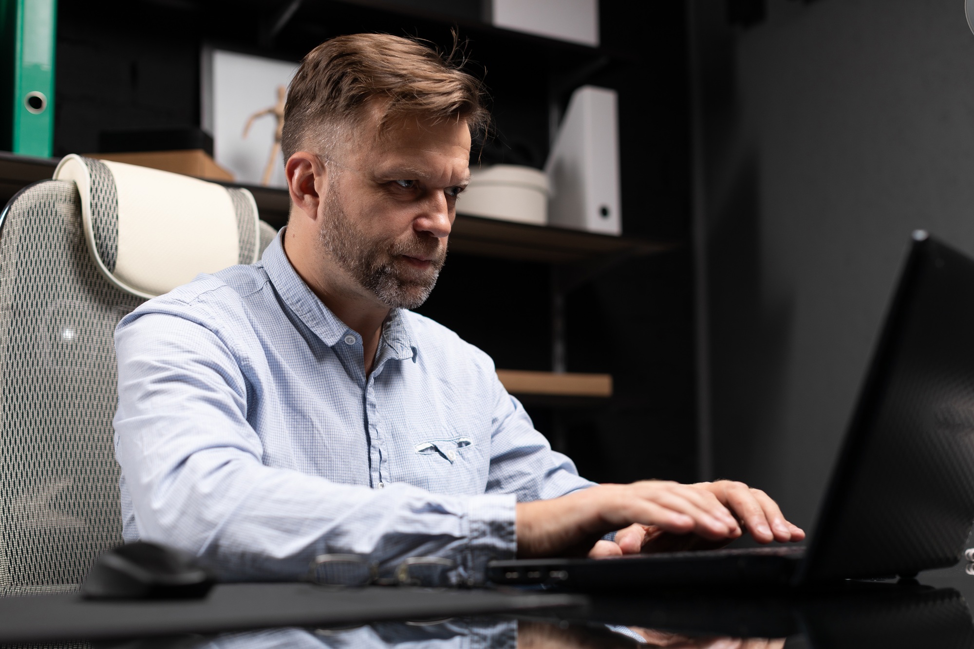 Serious businessman typing on laptop in stylish, modern office