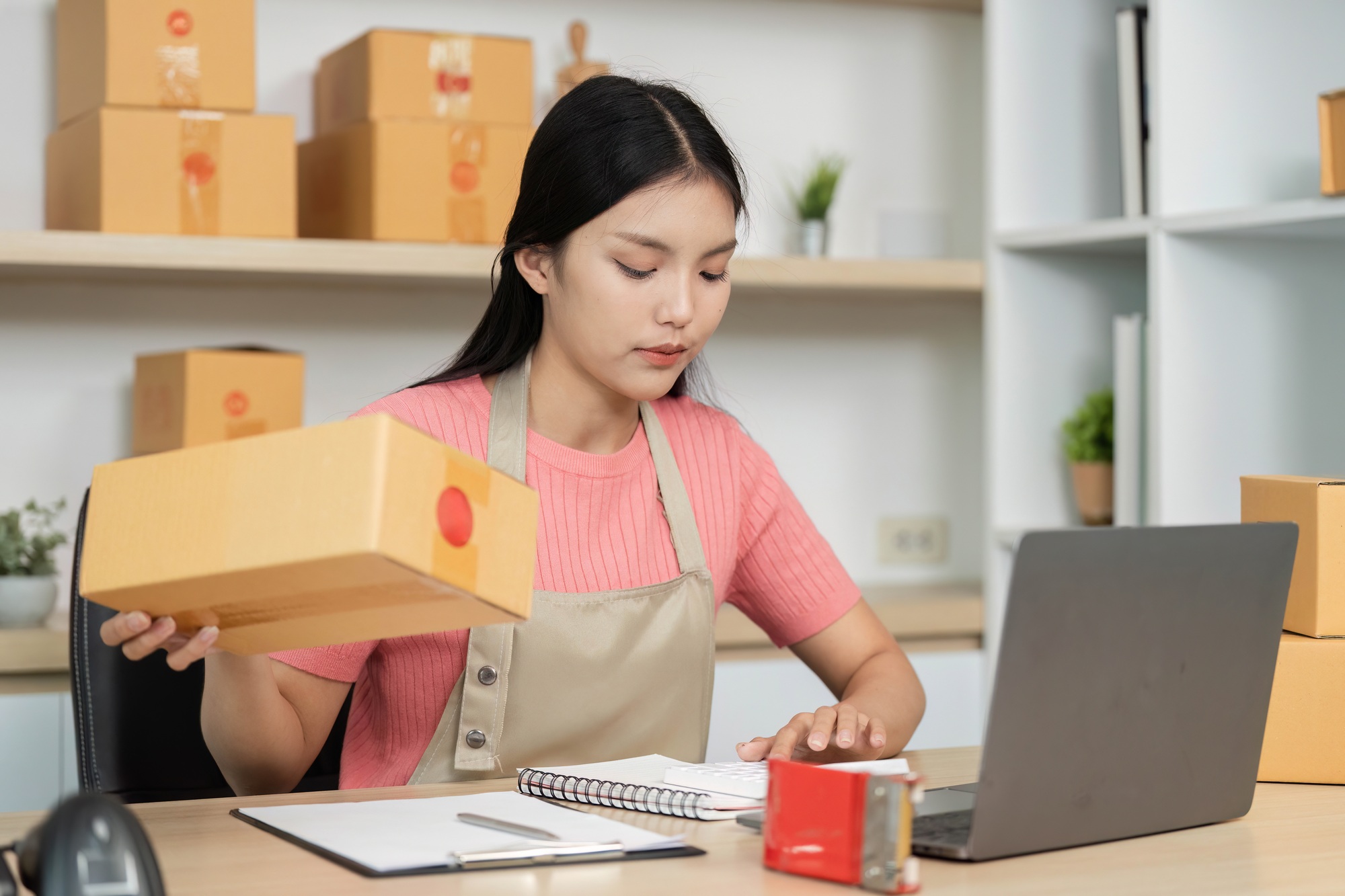 Small Business Operations. Female entrepreneur managing inventory and packaging orders.
