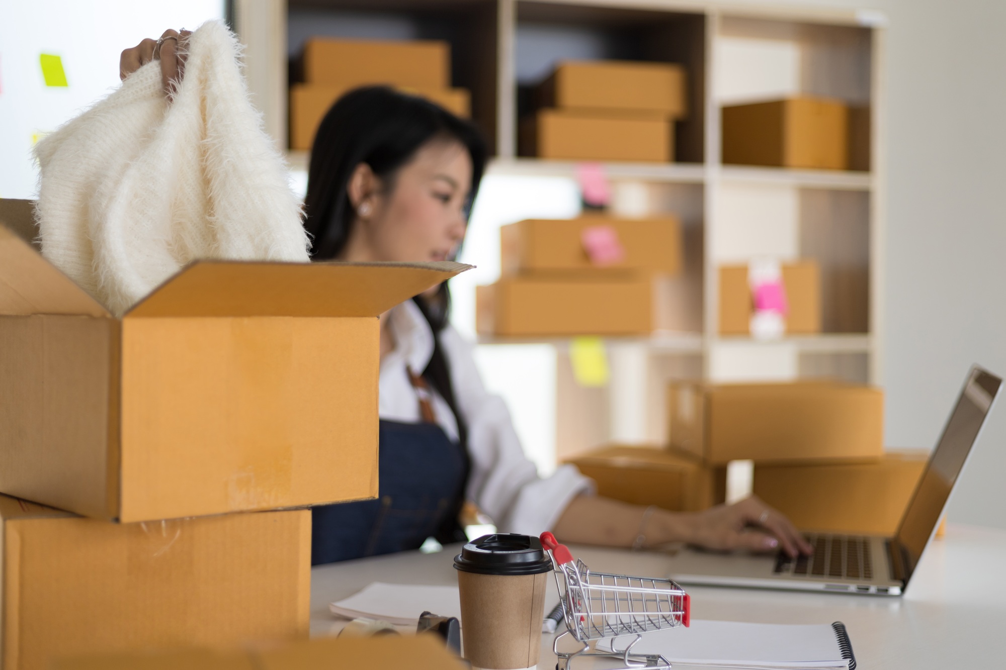 Small ecommerce business owner is working on a laptop to check online orders and pack for delivery.