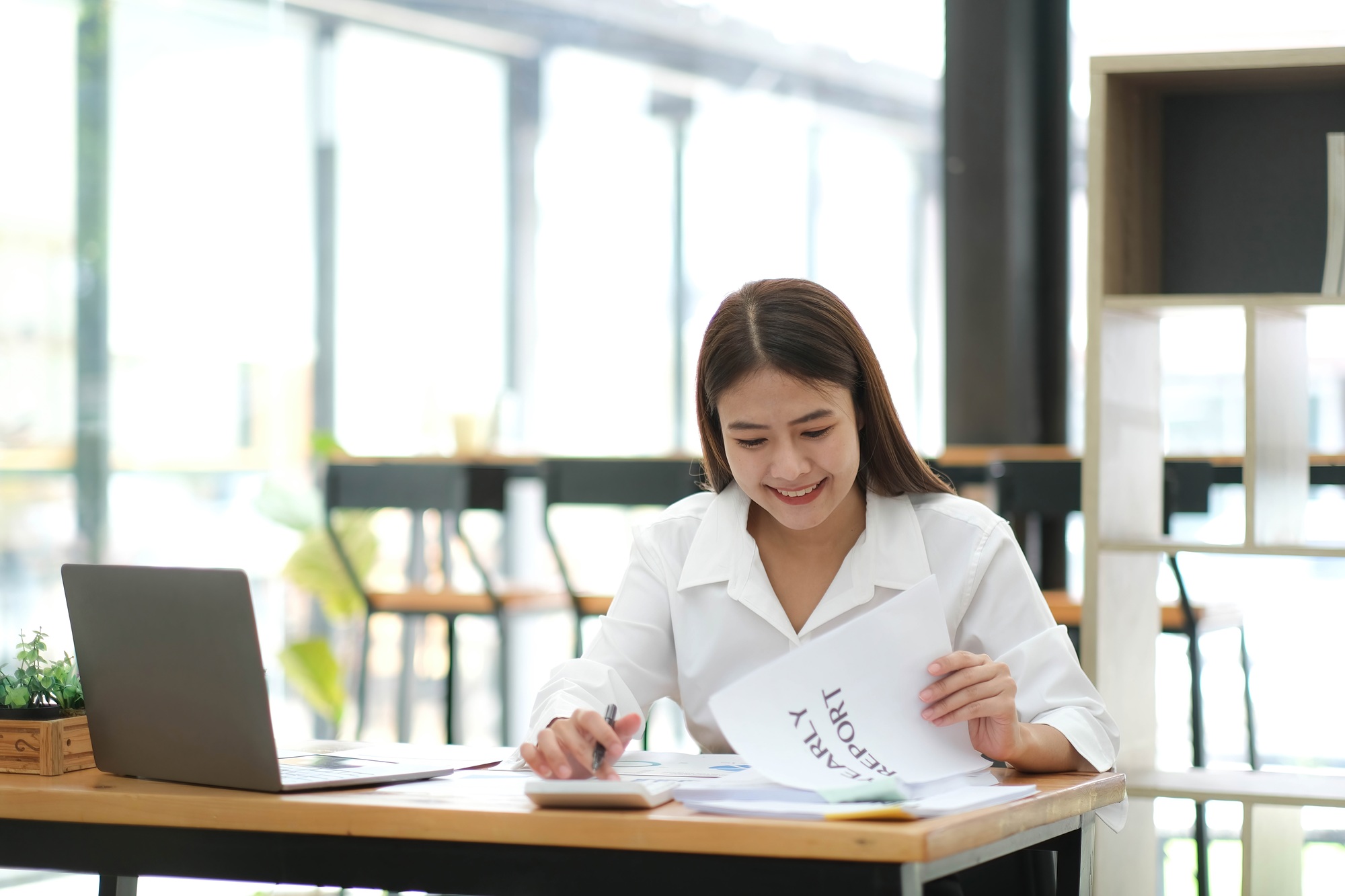 Smiling beautiful Asian businesswoman analyzing chart and graph showing changes