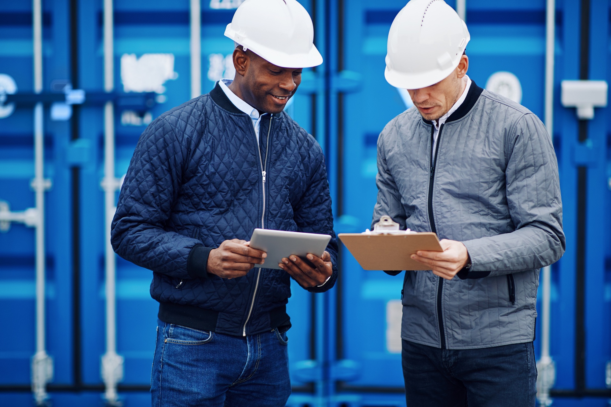 Smiling engineers standing in a shipping yard tracking inventory