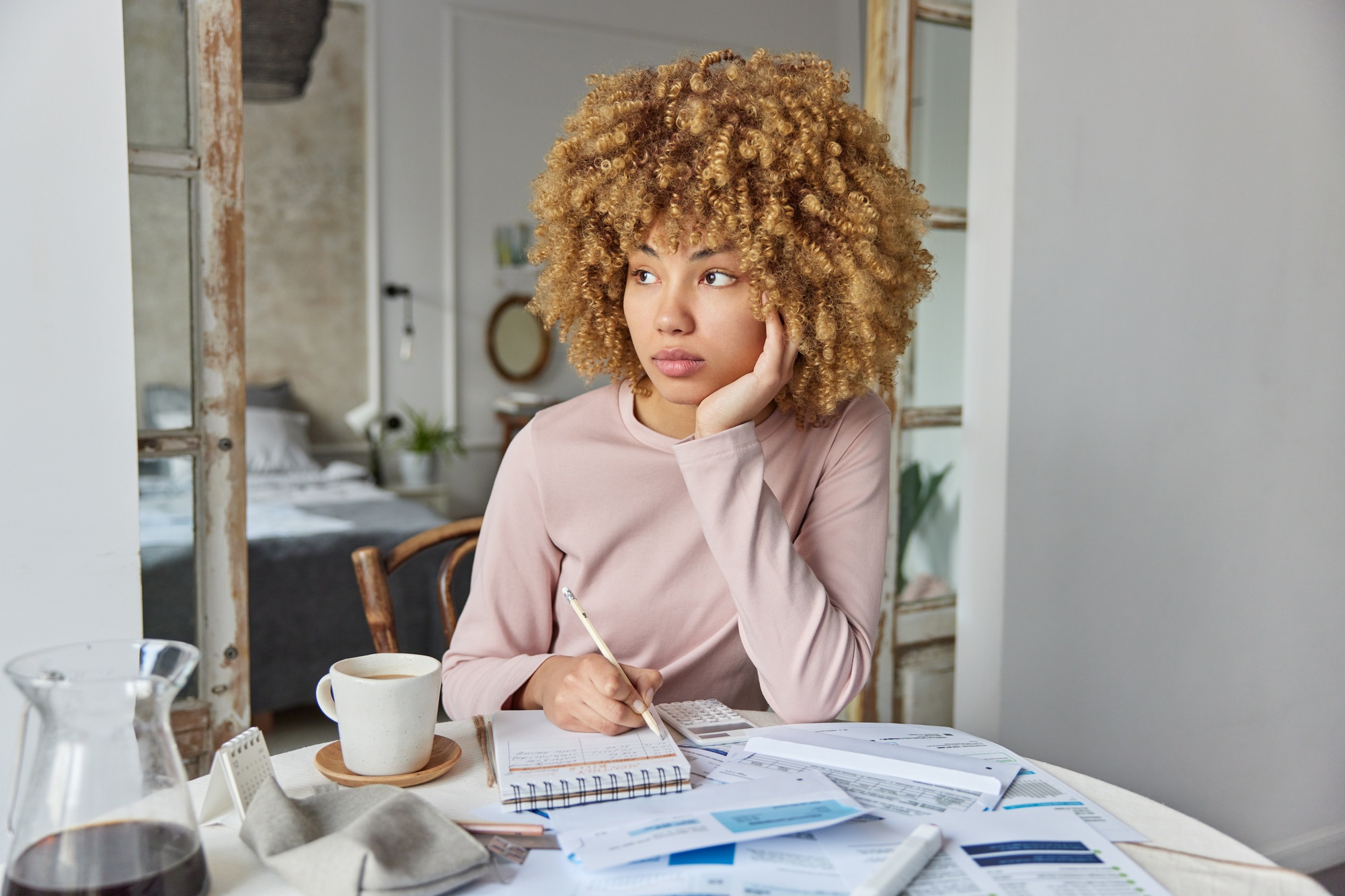 Thoughtful woman reviews bills and documents counts tax fees on calculator plans savings economy
