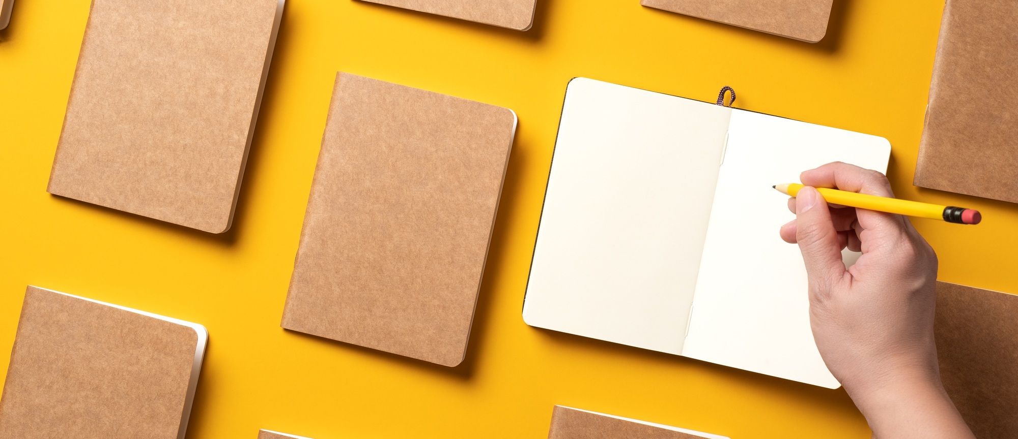 .top view of hand writing on open notebook align with kraft paper book