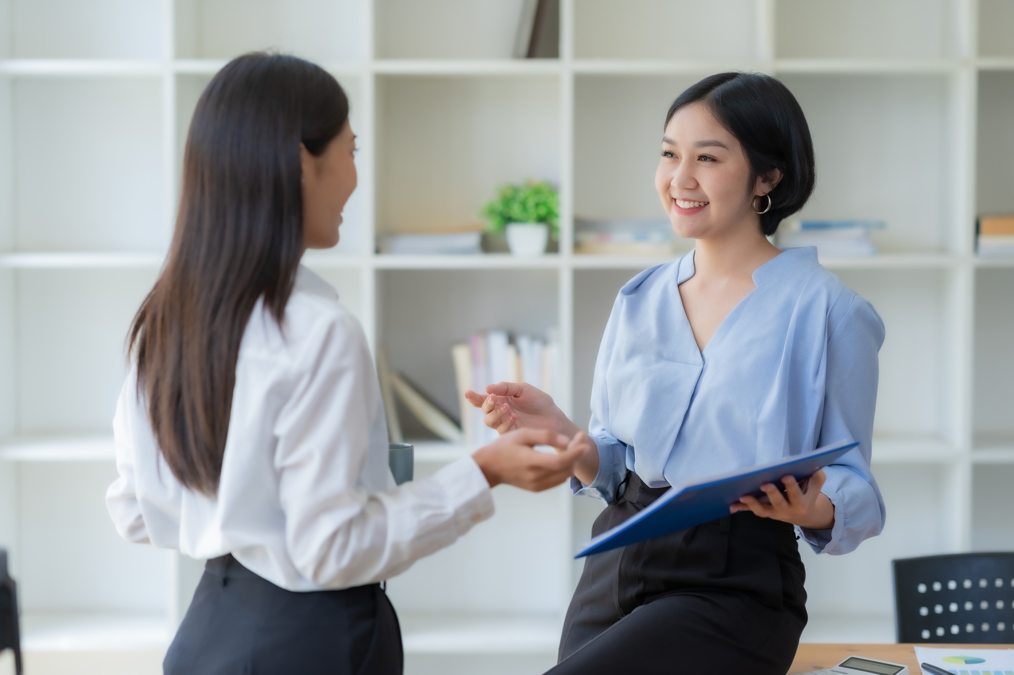 Two Asian businesswomen are consulting on marketing planning, a new corporate sales strategy