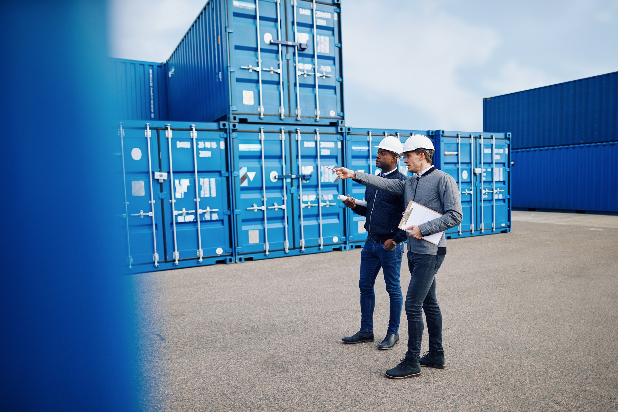 Two engineers tracking shipping inventory in a freight container yard