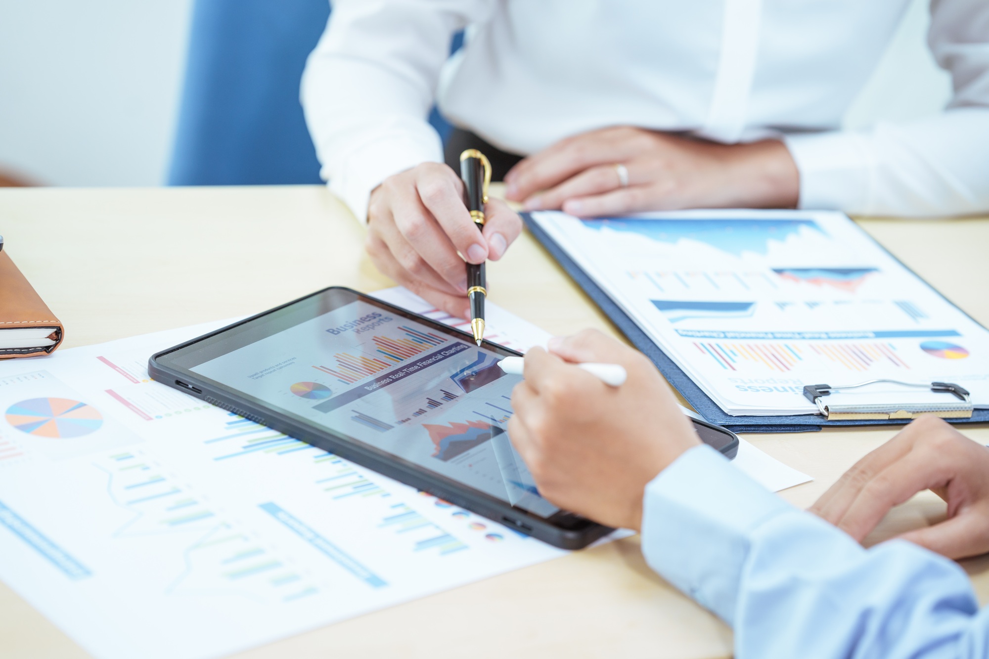 Two young Asian businesswomen sit at a table, engaged in a meeting.examine graphs and discuss