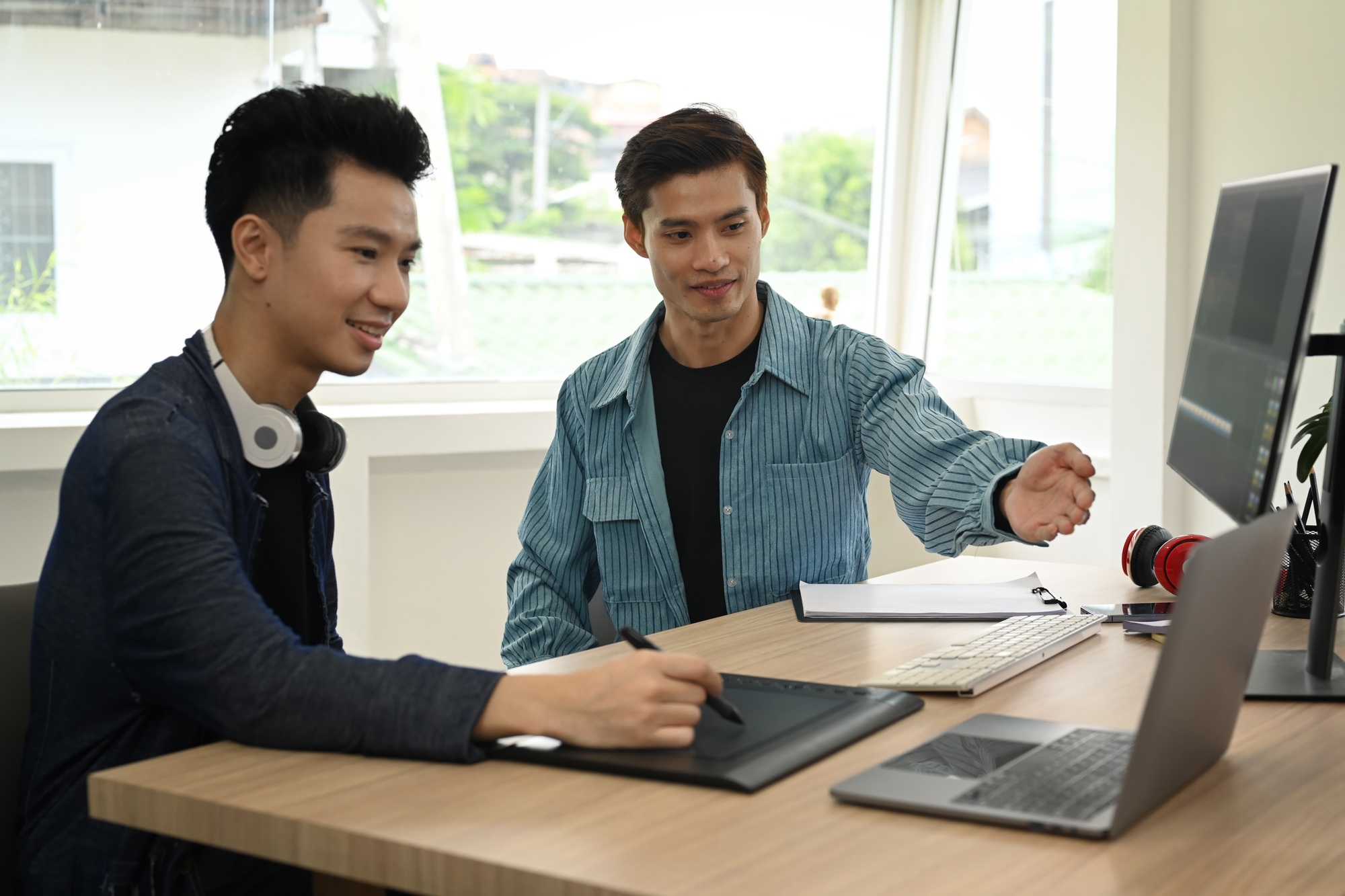 Two young content creator working together, editing video footage with professional computer.
